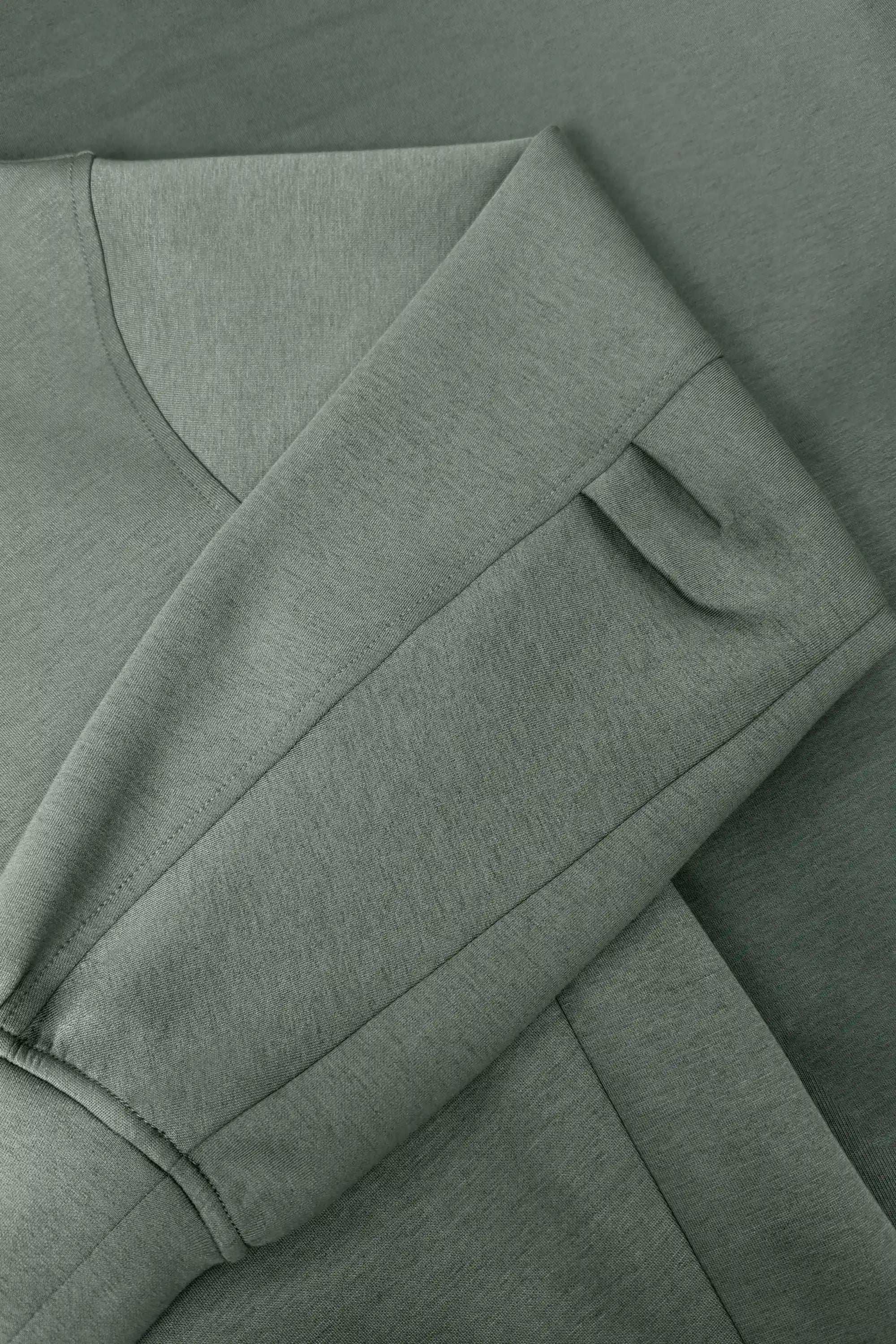 Close-up of women’s sage grey knit polo sweatshirt showing the structured sleeve and wide cuff detail