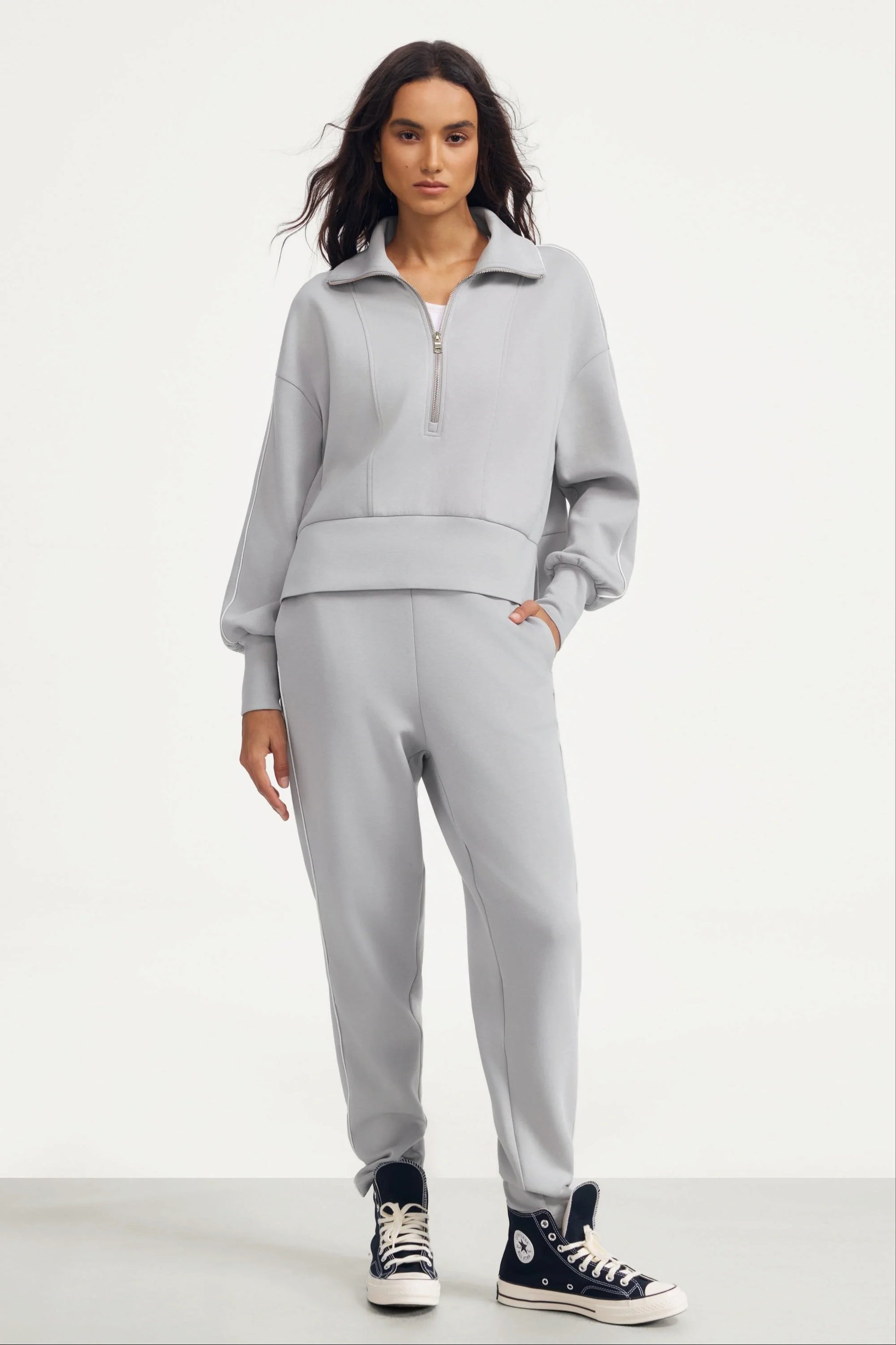 Woman wearing Soft Cloud Grey slim fit golf pants with a matching half-zip top