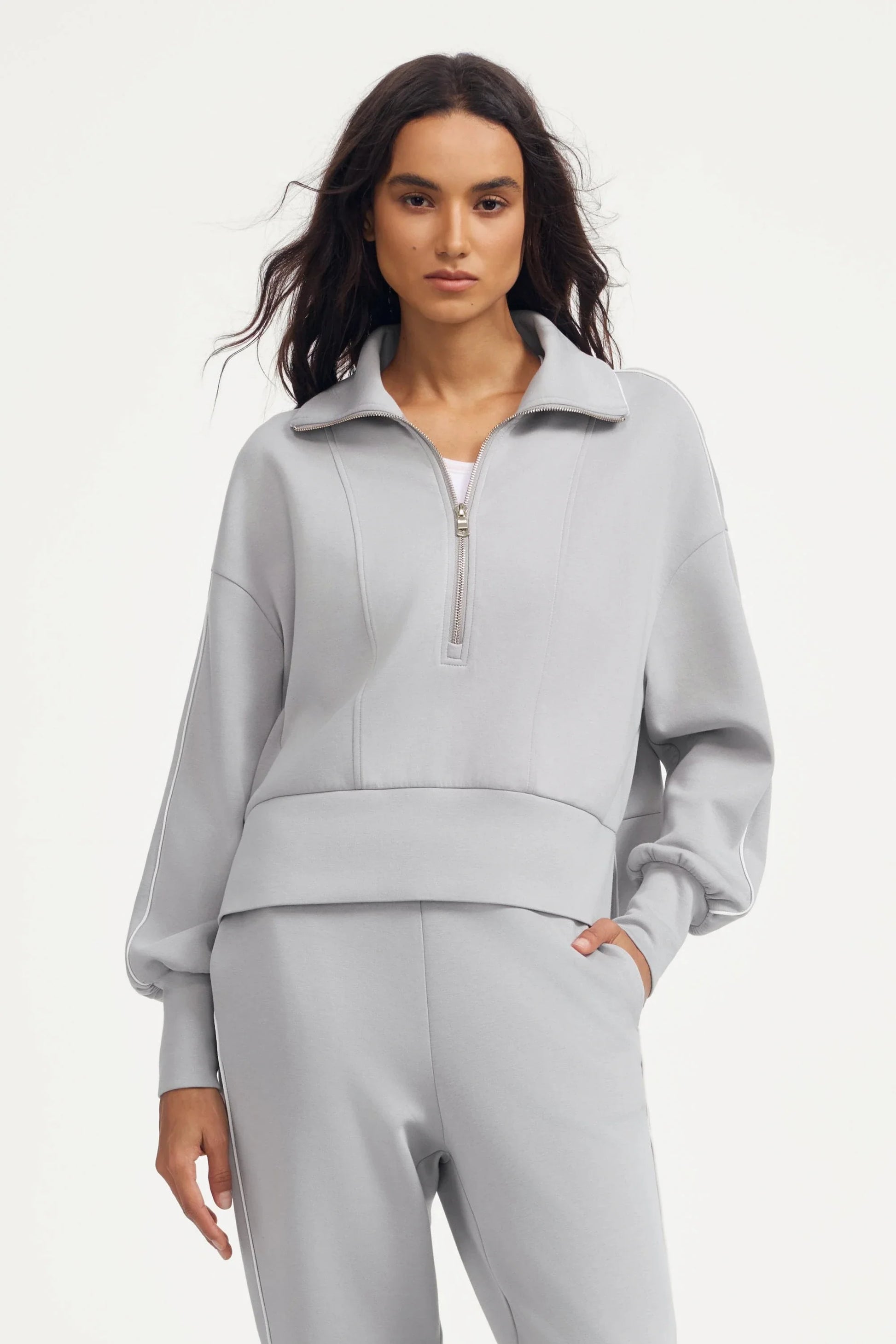 Woman wearing a women’s half-zip golf pullover in Soft Cloud Grey with matching pants, front view