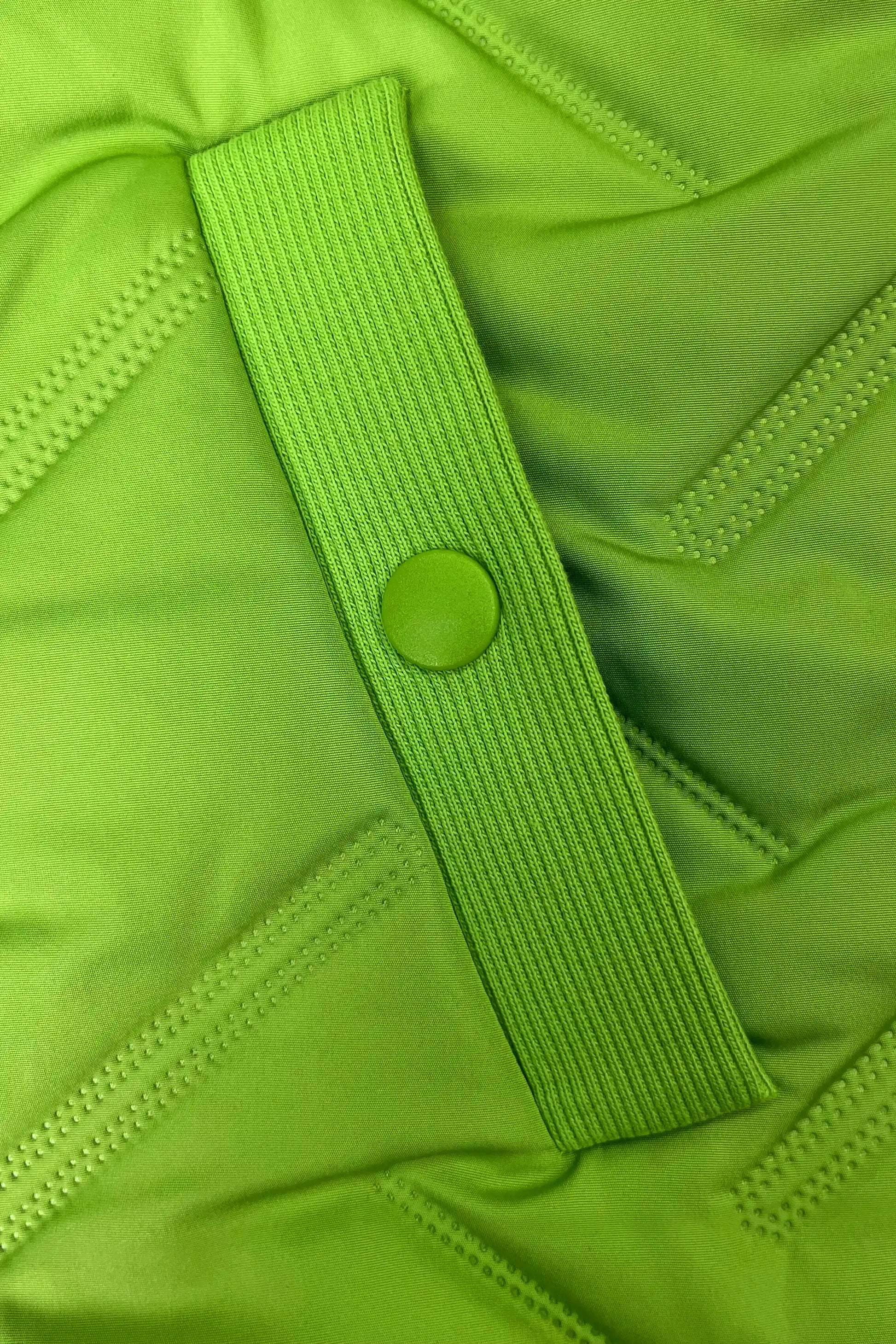 Close-up of women’s bright green lightweight puffer vest showing the pocket area, quilted construction and ribbed trim