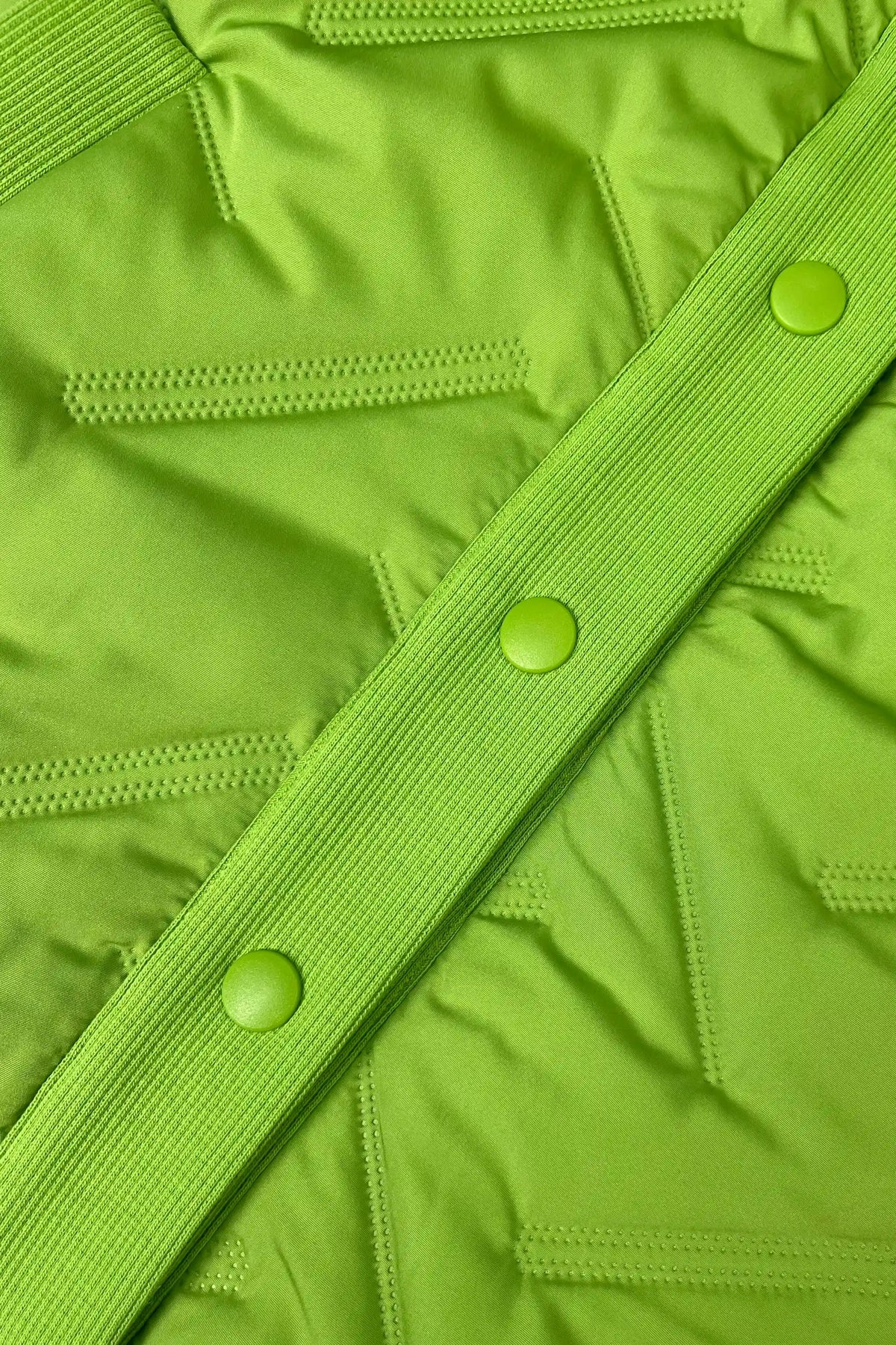 Close-up of women’s bright green lightweight puffer vest with quilted construction, ribbed placket and tonal buttons