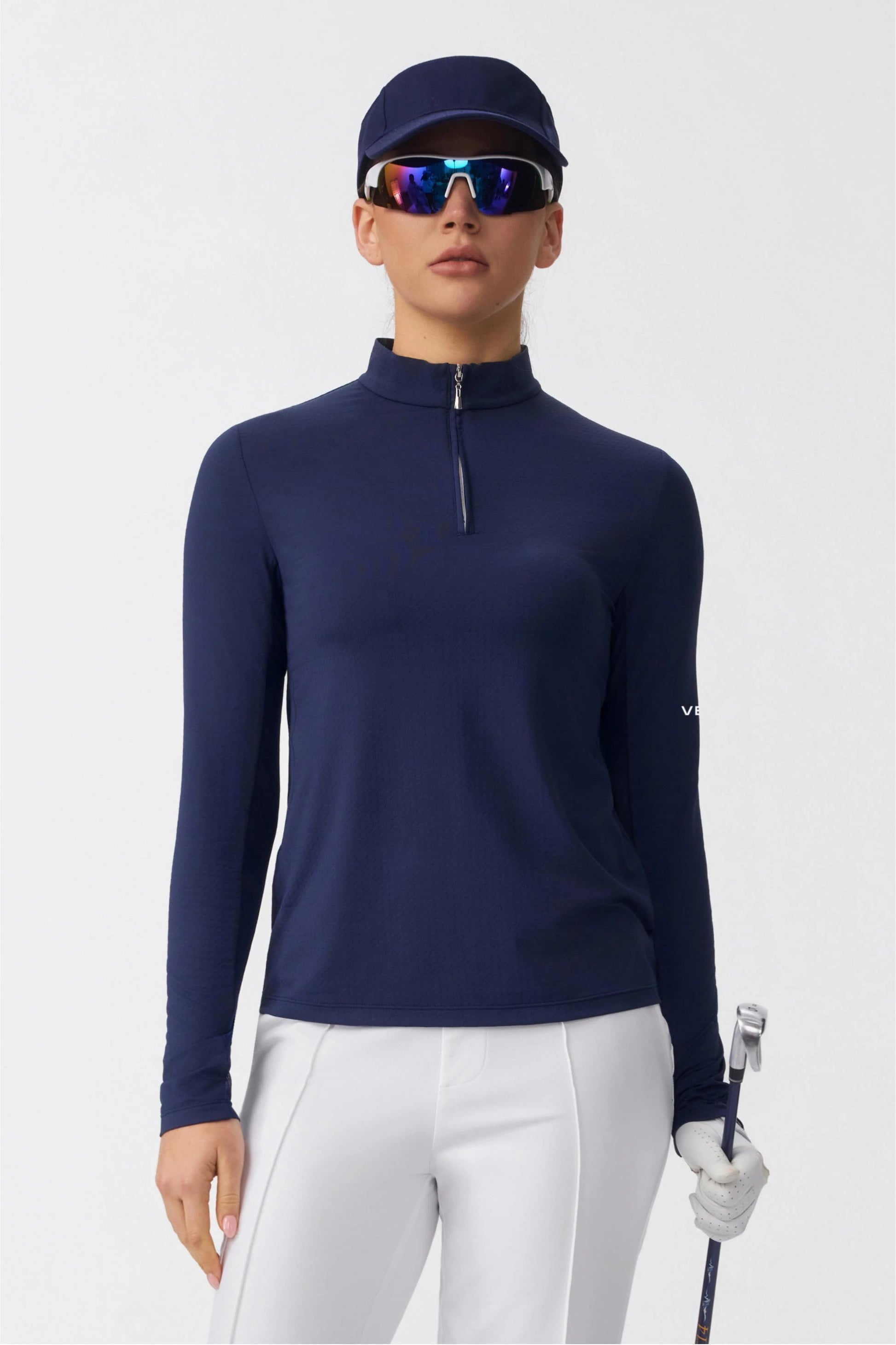 Front view of a navy long sleeve zip neck golf top worn with white golf pants