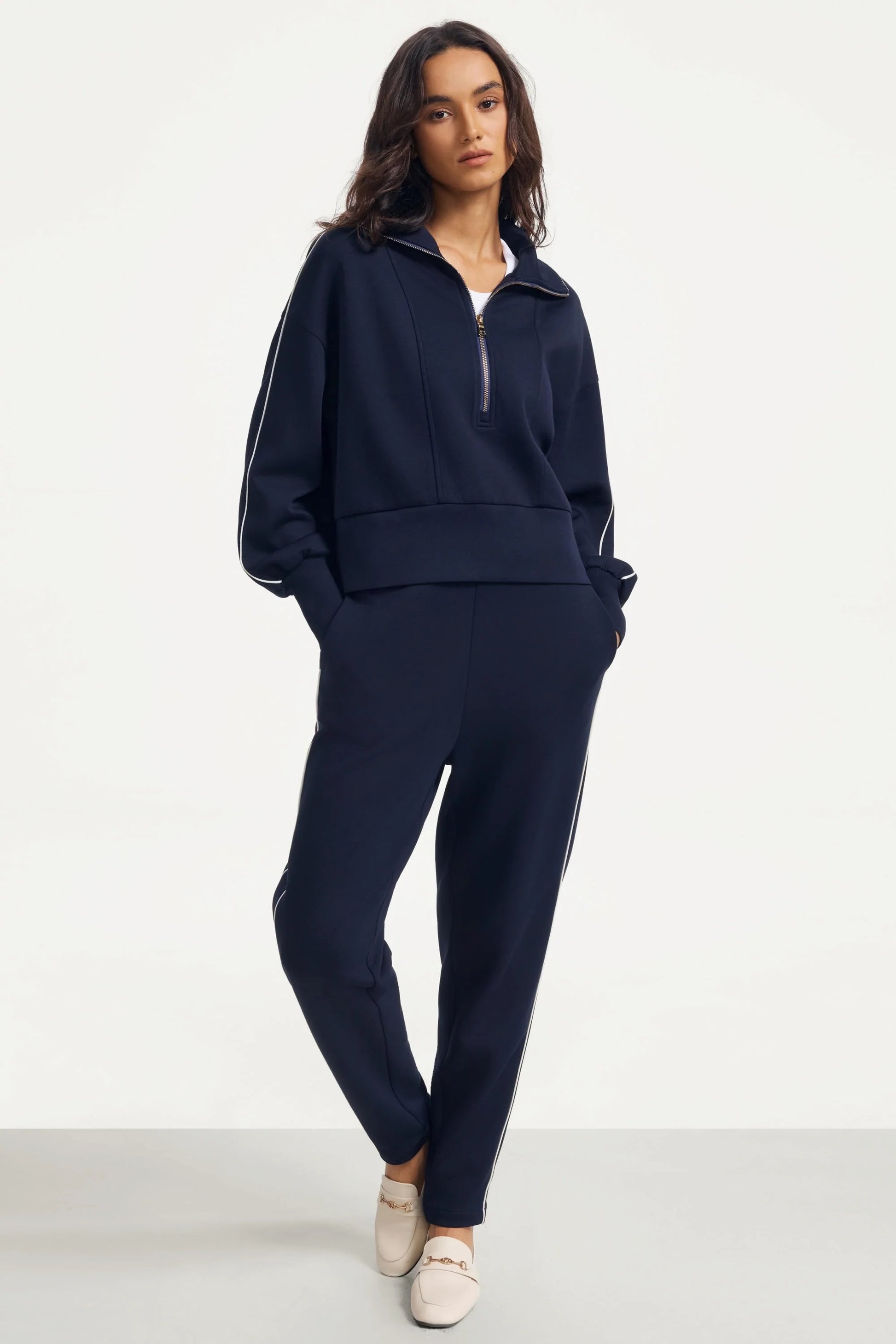 Woman wearing Midnight Navy slim fit golf pants styled with a matching half-zip top