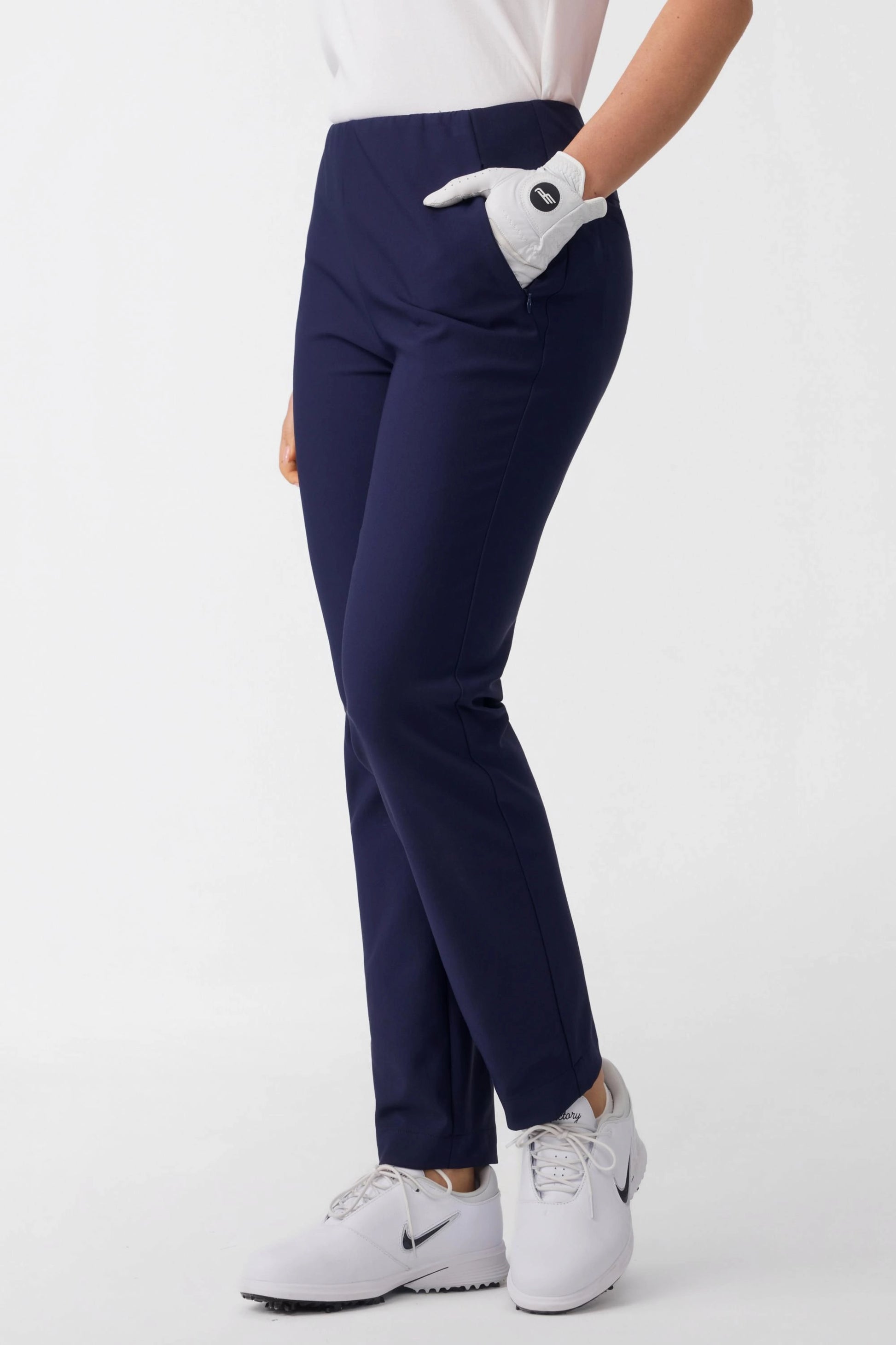 Side view of women’s navy stretch golf pants with streamlined fit and functional side pocket