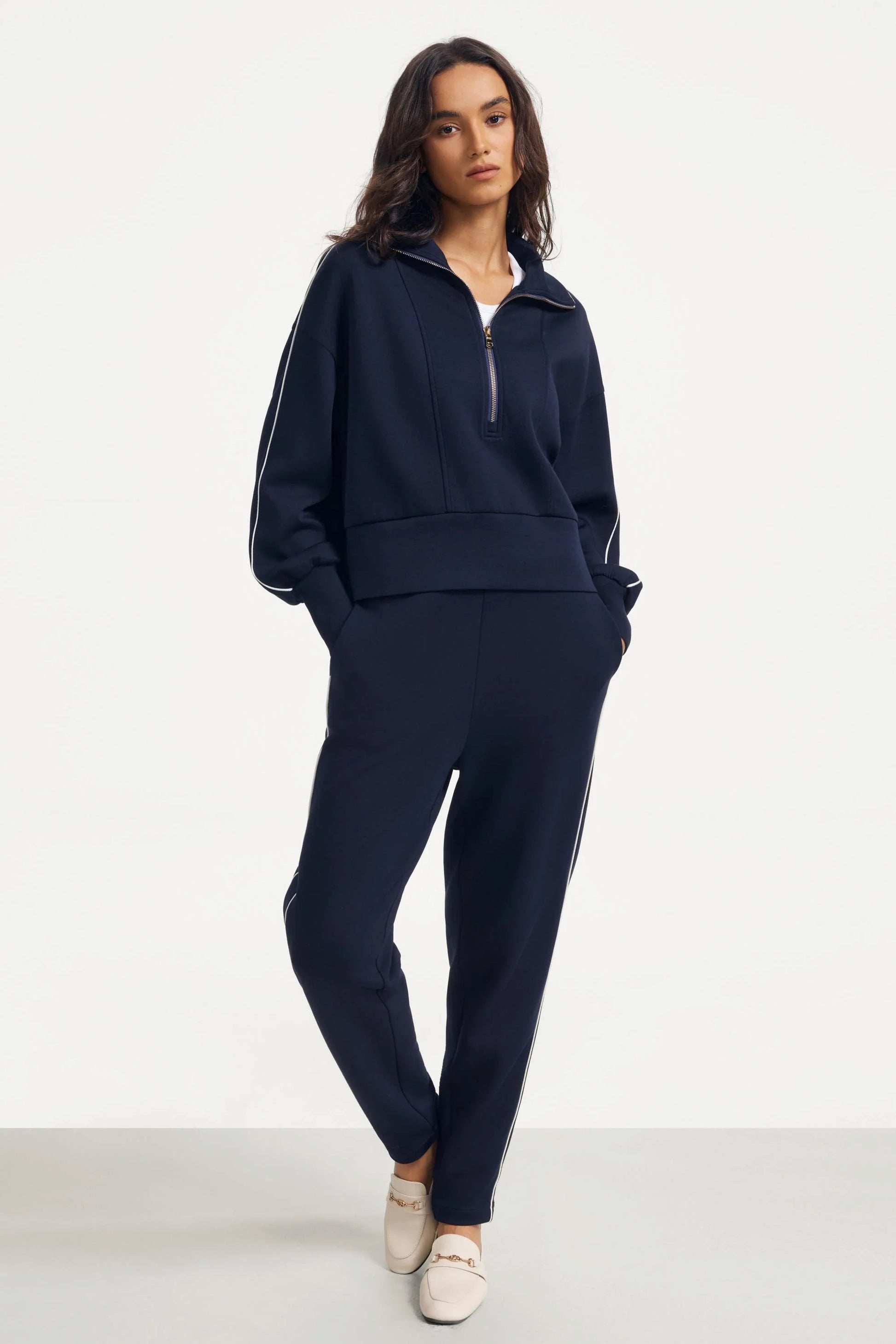 Full outfit of a woman wearing a women’s half-zip golf pullover in Midnight Navy with matching slim fit pants