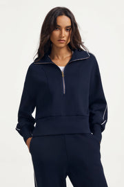 Woman wearing a women’s half-zip golf pullover in Midnight Navy with a relaxed fit and matching pants