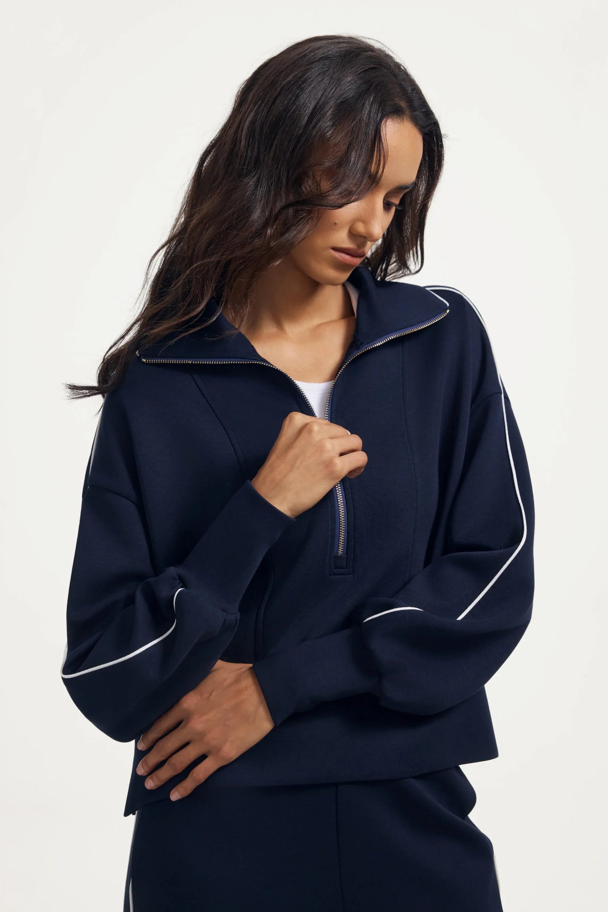 Woman adjusting the zipper on a women’s half-zip golf pullover in Midnight Navy, highlighting the neckline detail