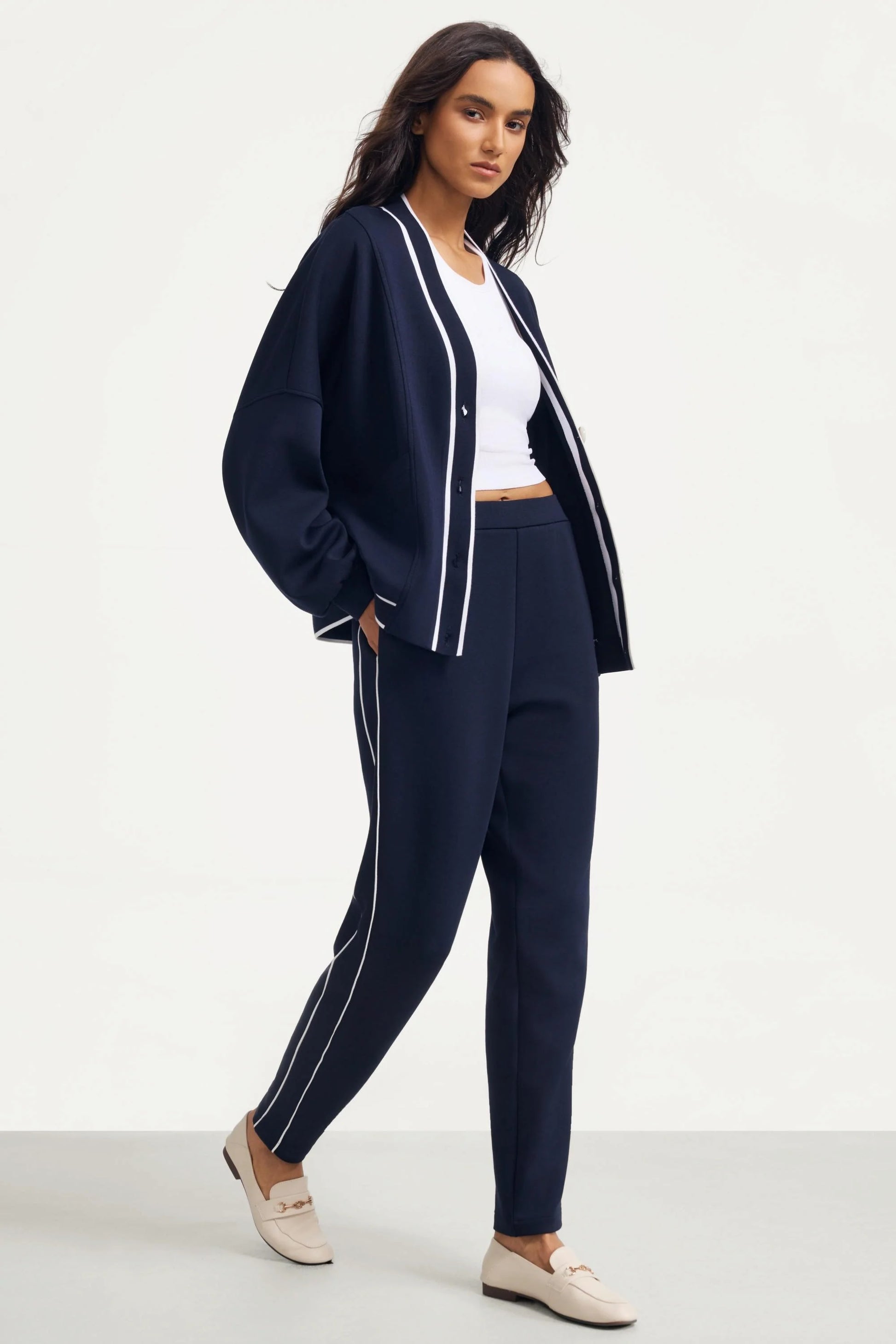 Woman wearing Midnight Navy track pants styled with a matching cardigan and white top