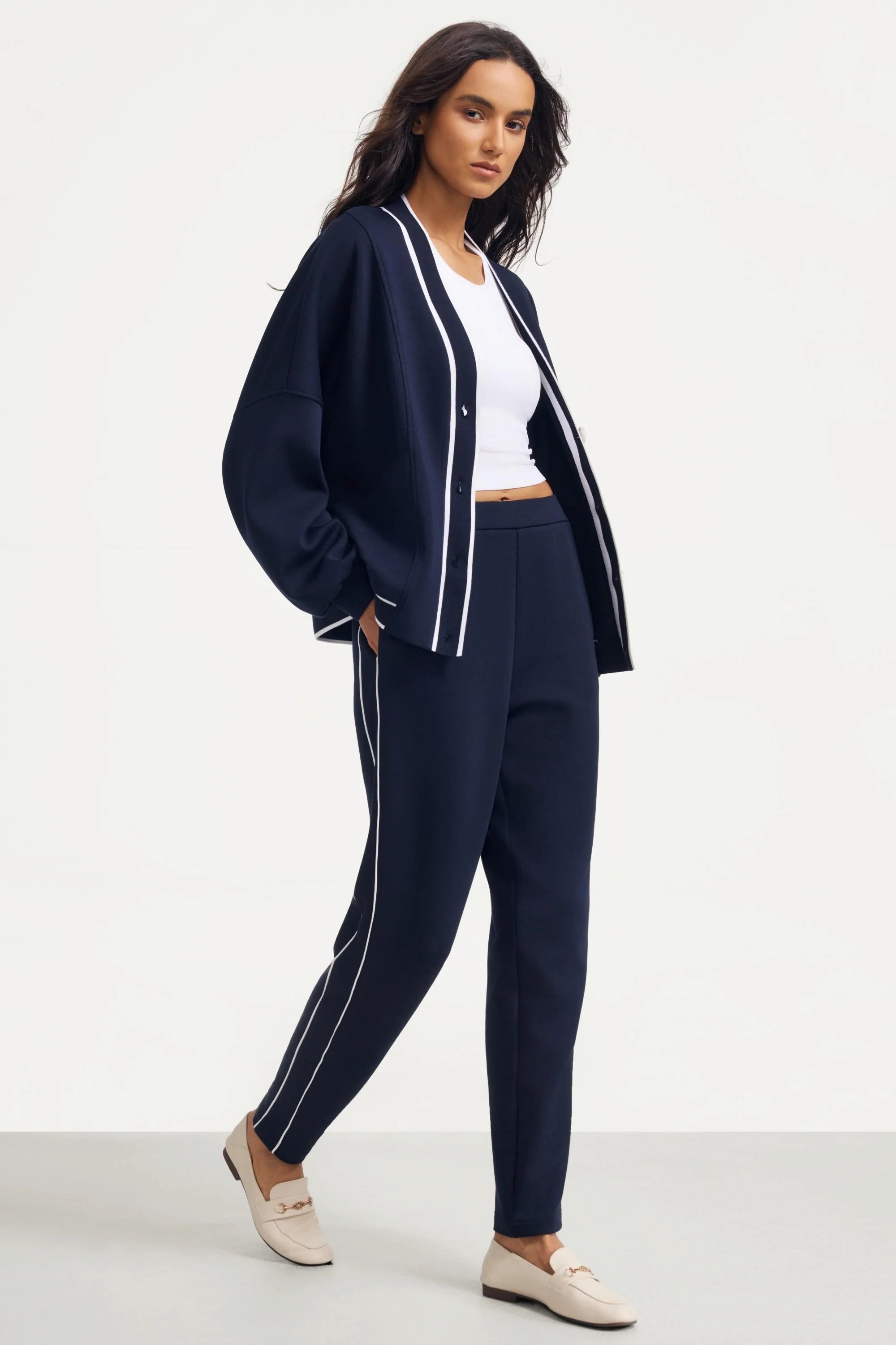 Woman wearing Midnight Navy track pants styled with a matching cardigan and white top