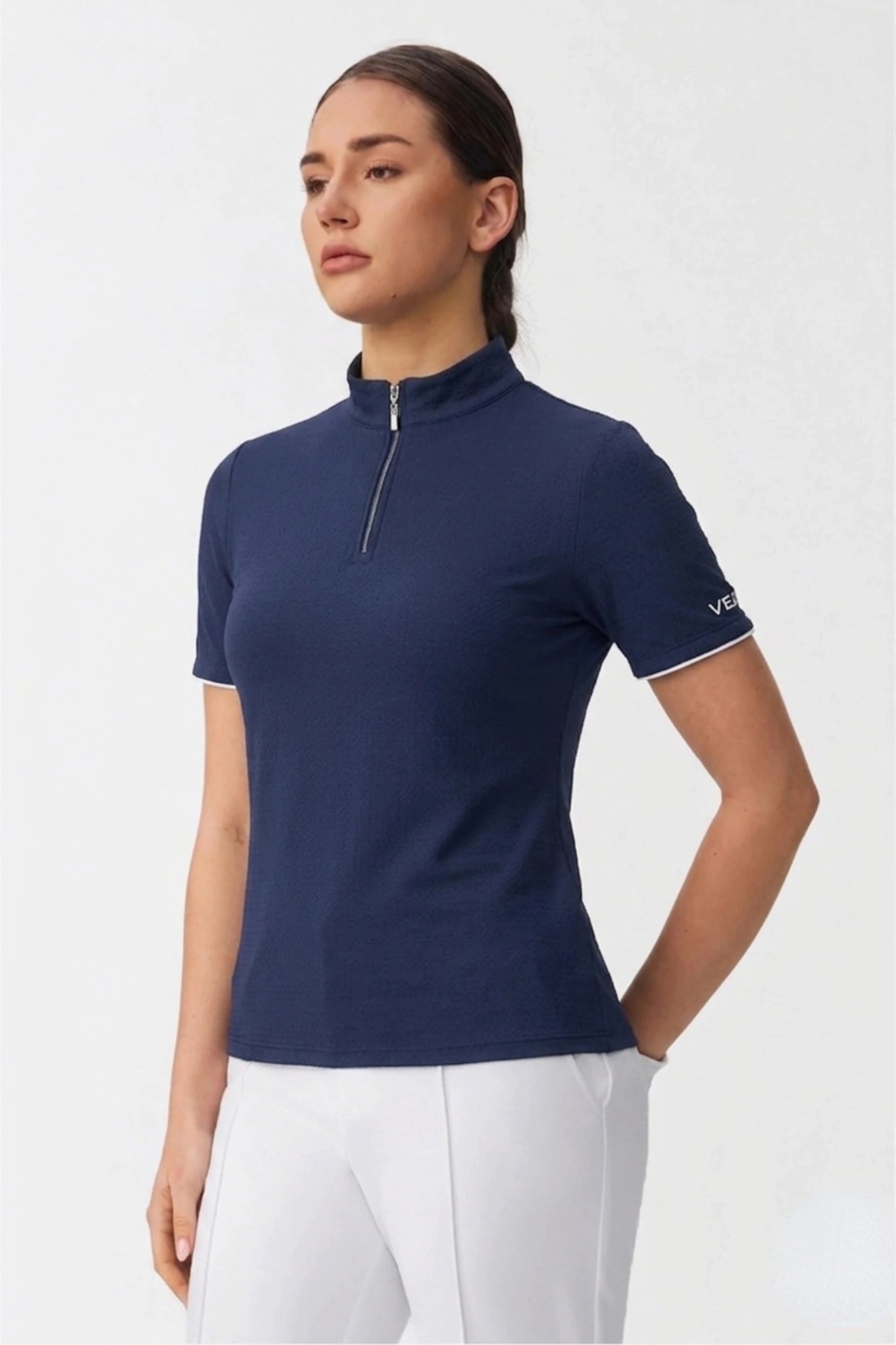 Close-up of women’s navy zip-neck golf shirt showing the collar, zipper detail, and refined finish