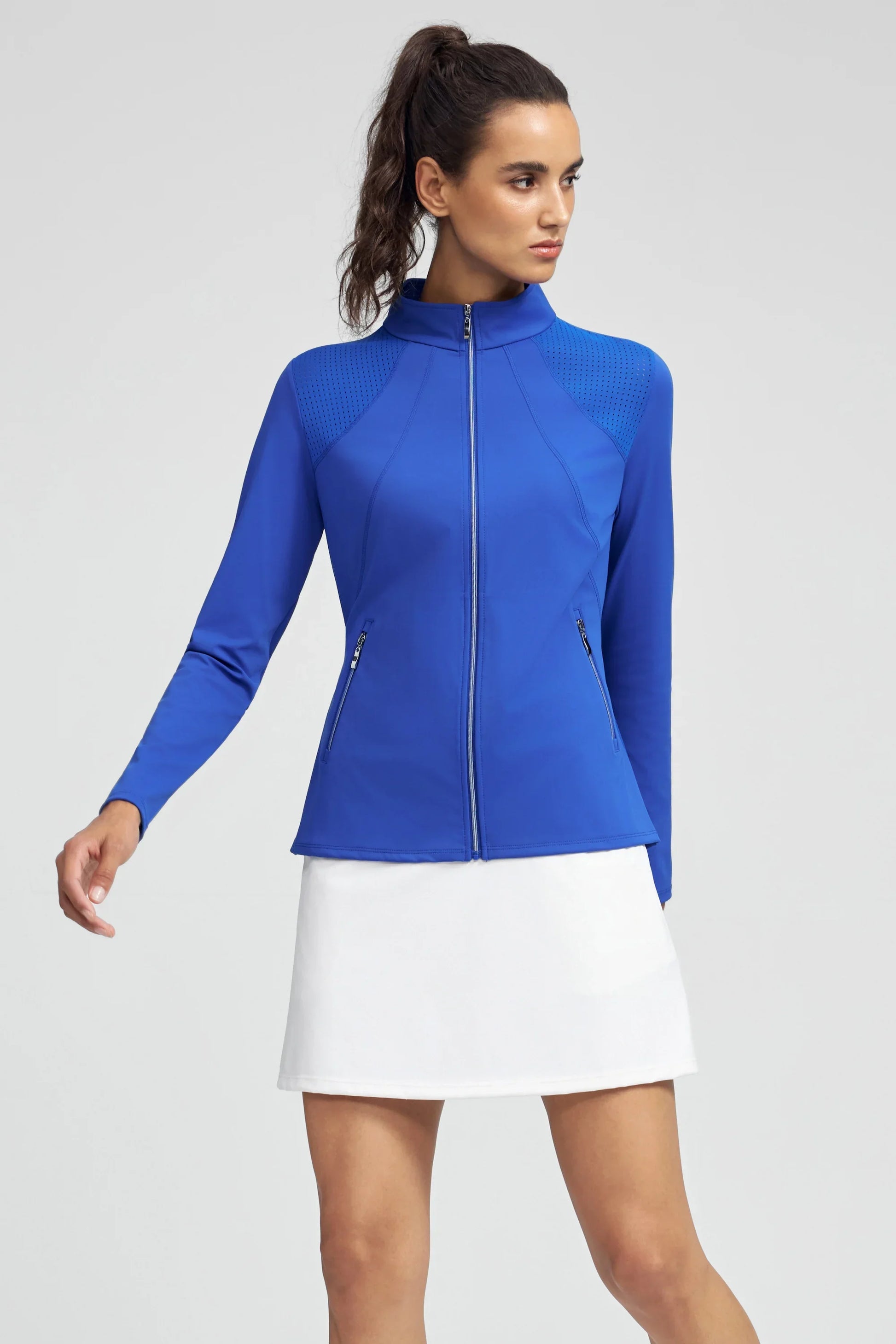 Woman wearing Cobalt Bloom peplum mesh-panel zip golf jacket with white golf skirt