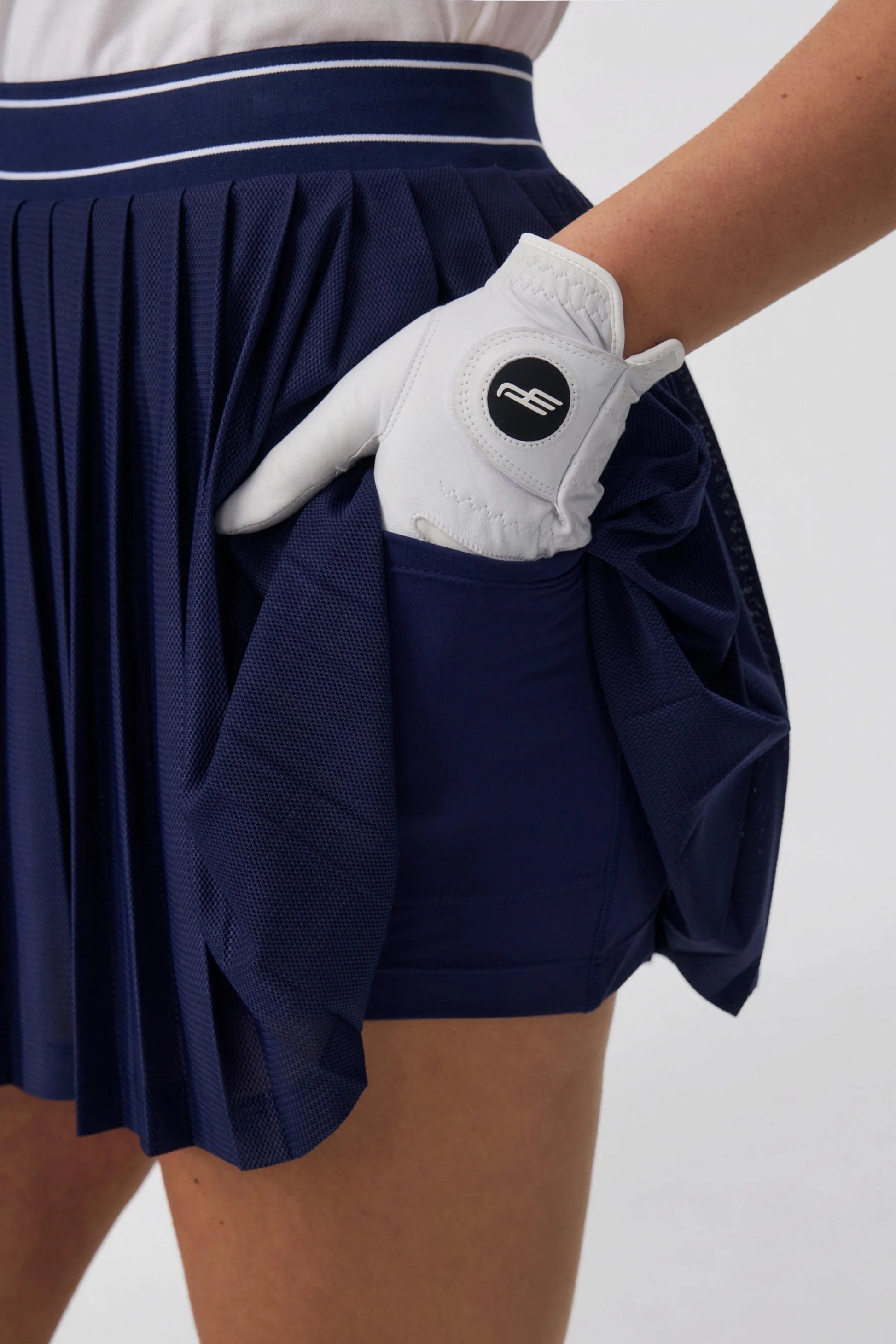 Detail of women’s navy pleated golf skort with built-in shorts and side pocket
