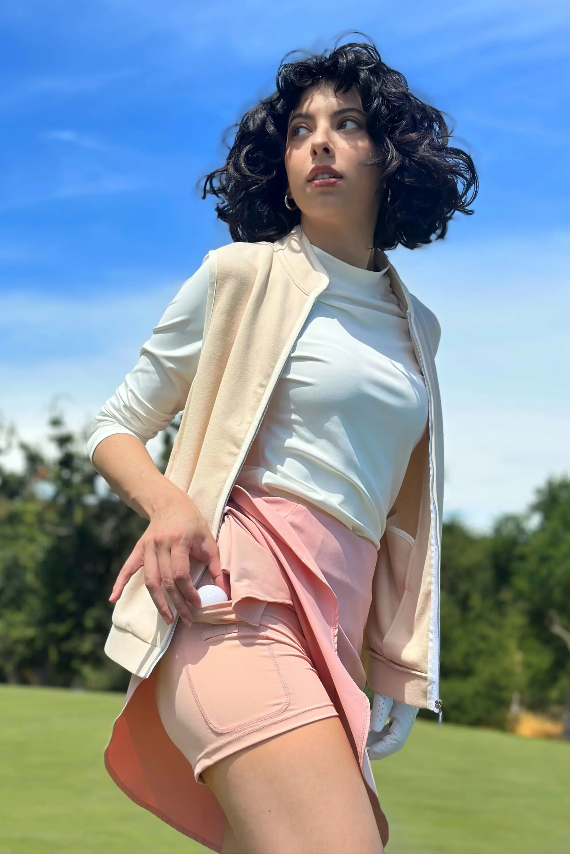 Woman wearing a Sandstone zip-front golf vest layered over a long-sleeve top on the course