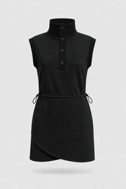 Front view of women's black sleeveless golf dress with buttoned stand collar, drawcord waist and asymmetric wrap hem