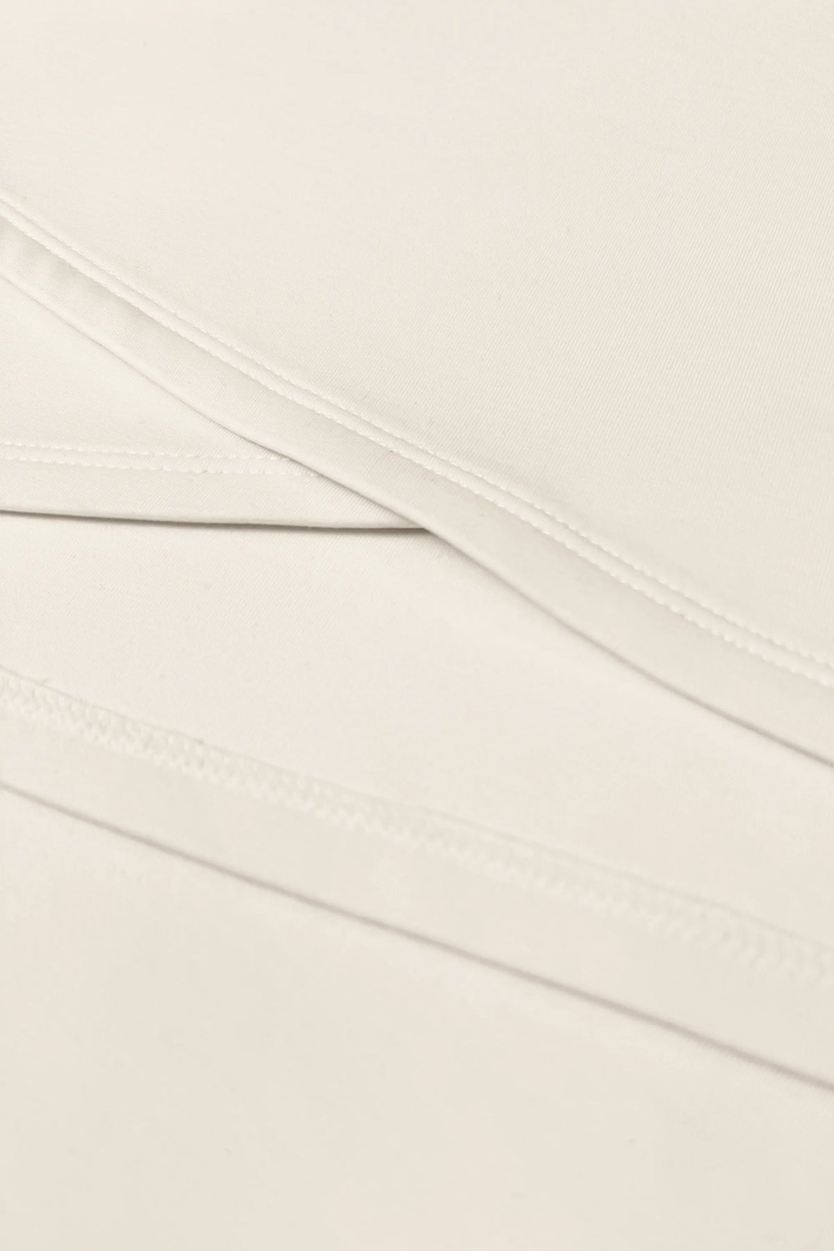 Close-up of the asymmetric wrap construction and clean stitching on the Soft Ivory women’s golf dress