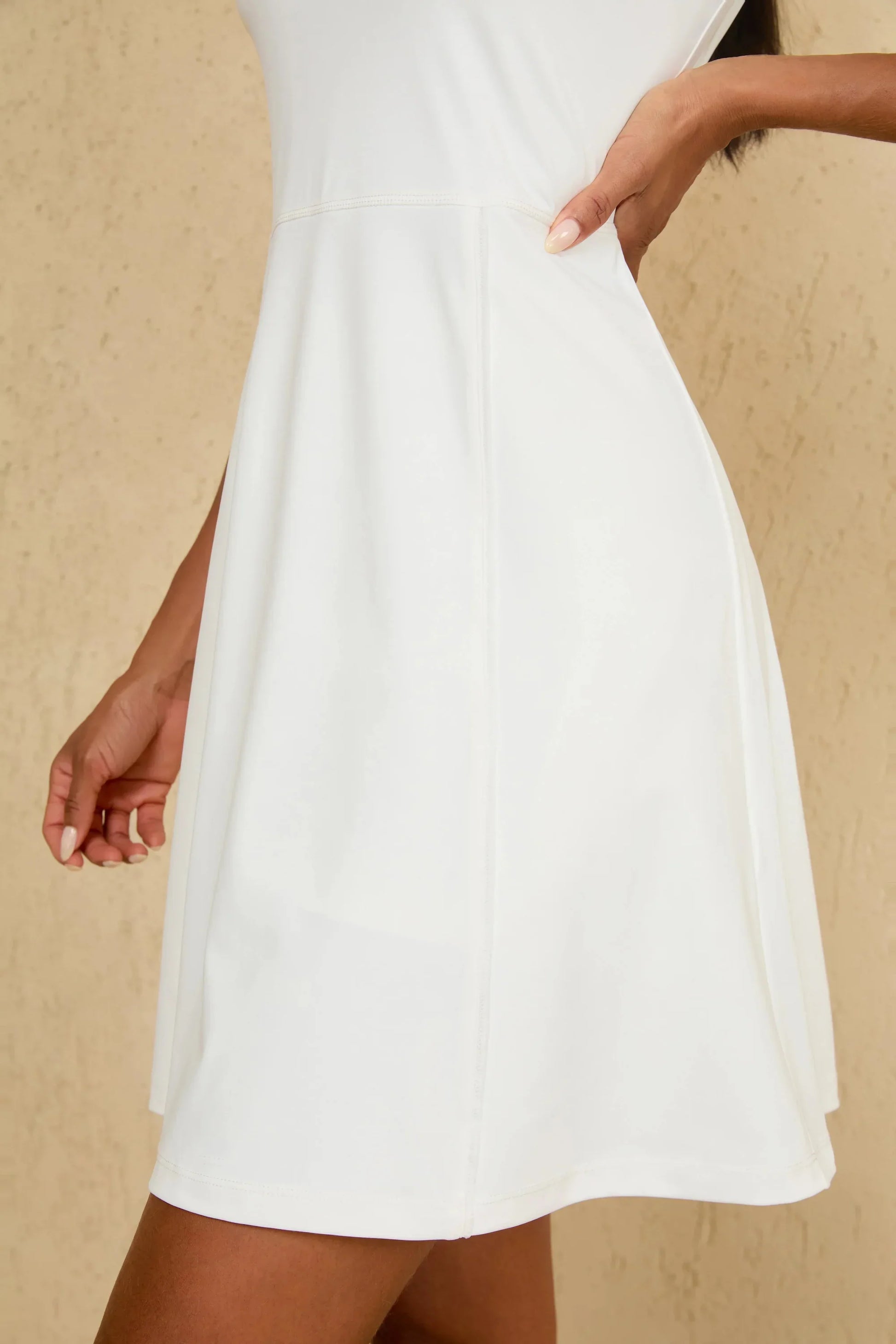 Close-up of hem detail on women’s white sleeveless golf dress