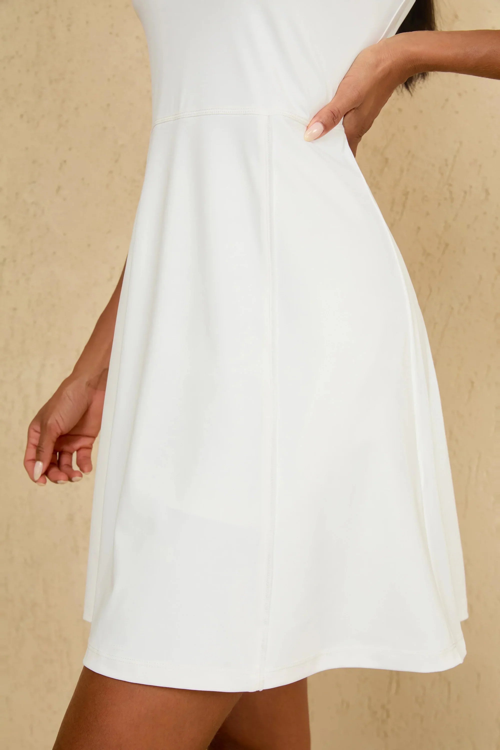 Close-up of hem detail on women’s white sleeveless golf dress