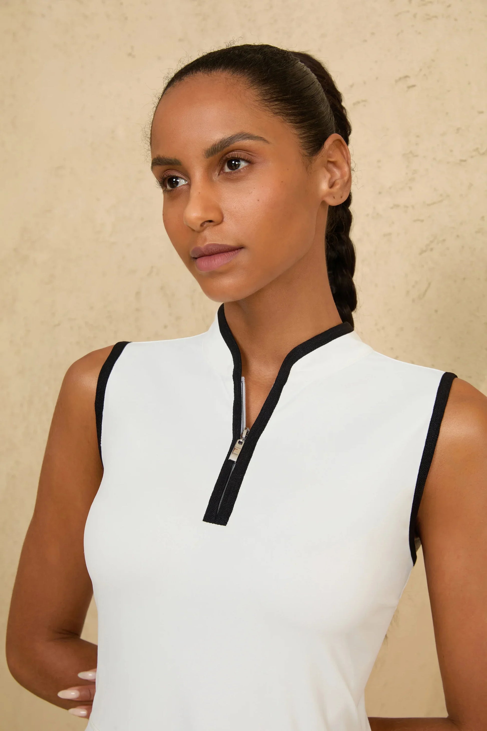 Close-up of half-zip collar detail on women’s white sleeveless golf dress