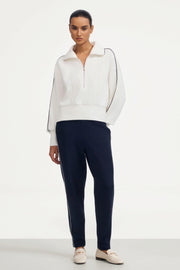 Women’s half-zip golf pullover in ivory shown in a full outfit with navy golf pants
