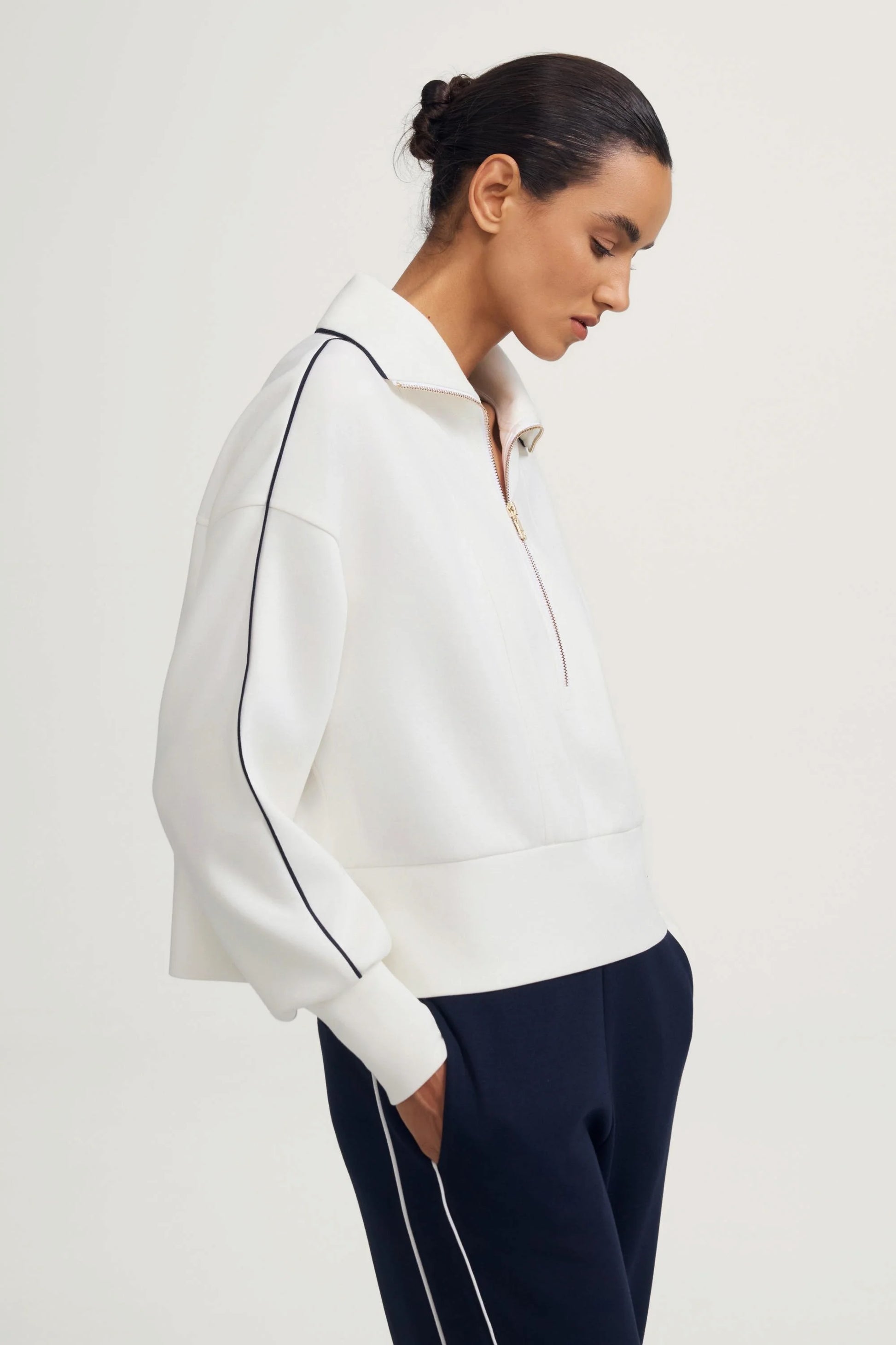 Side view of a women’s half-zip golf pullover in ivory showing the silhouette and sleeve shape