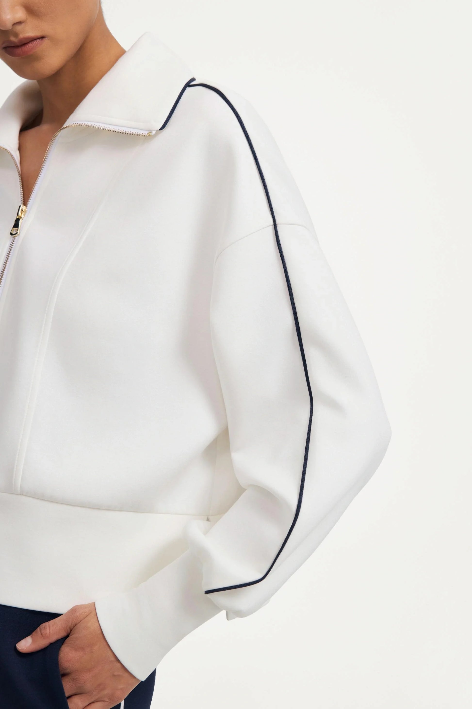 Close-up of sleeve detail on a women’s half-zip golf pullover in ivory with contrast piping