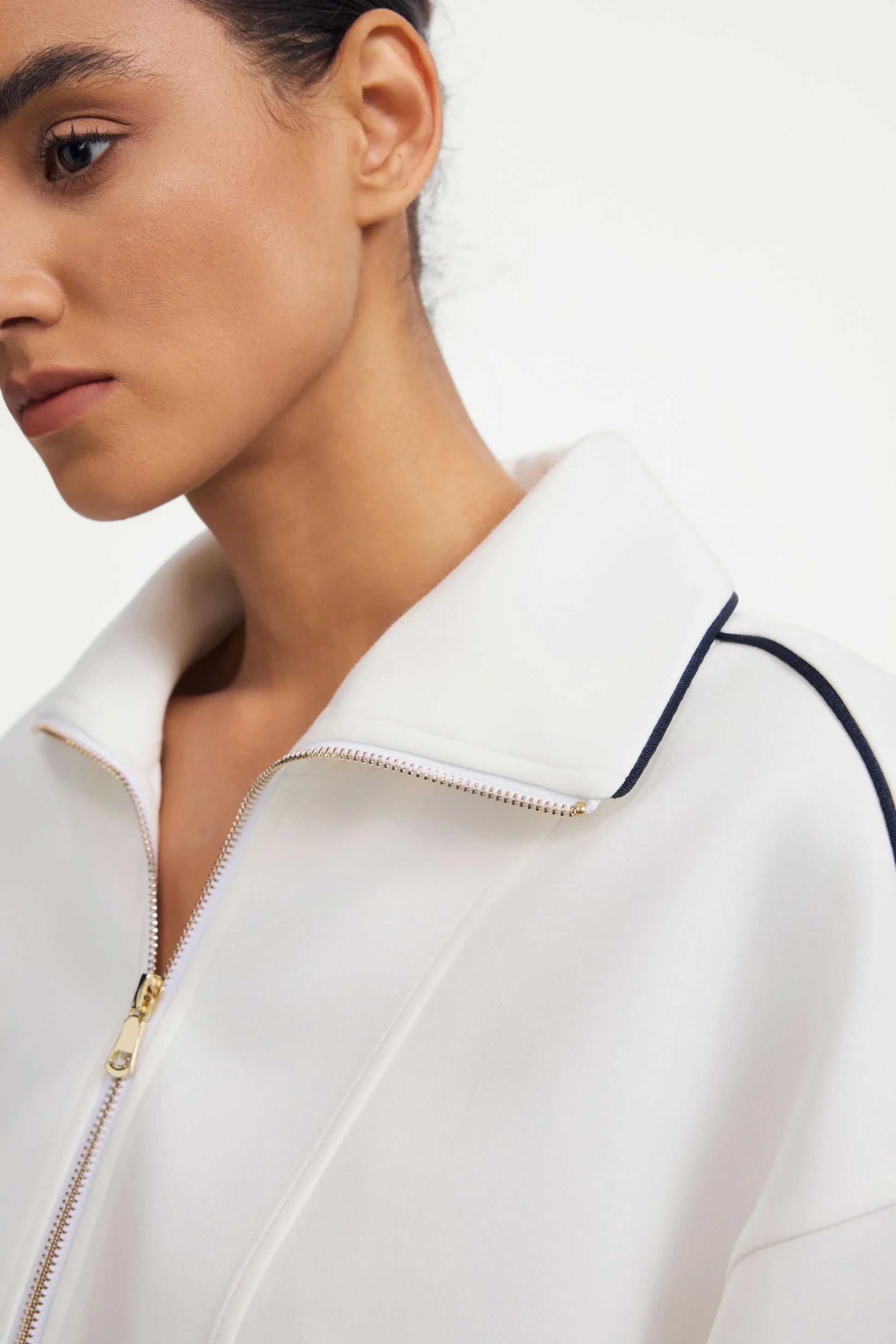 Close-up of zip collar detail on a women’s half-zip golf pullover in ivory