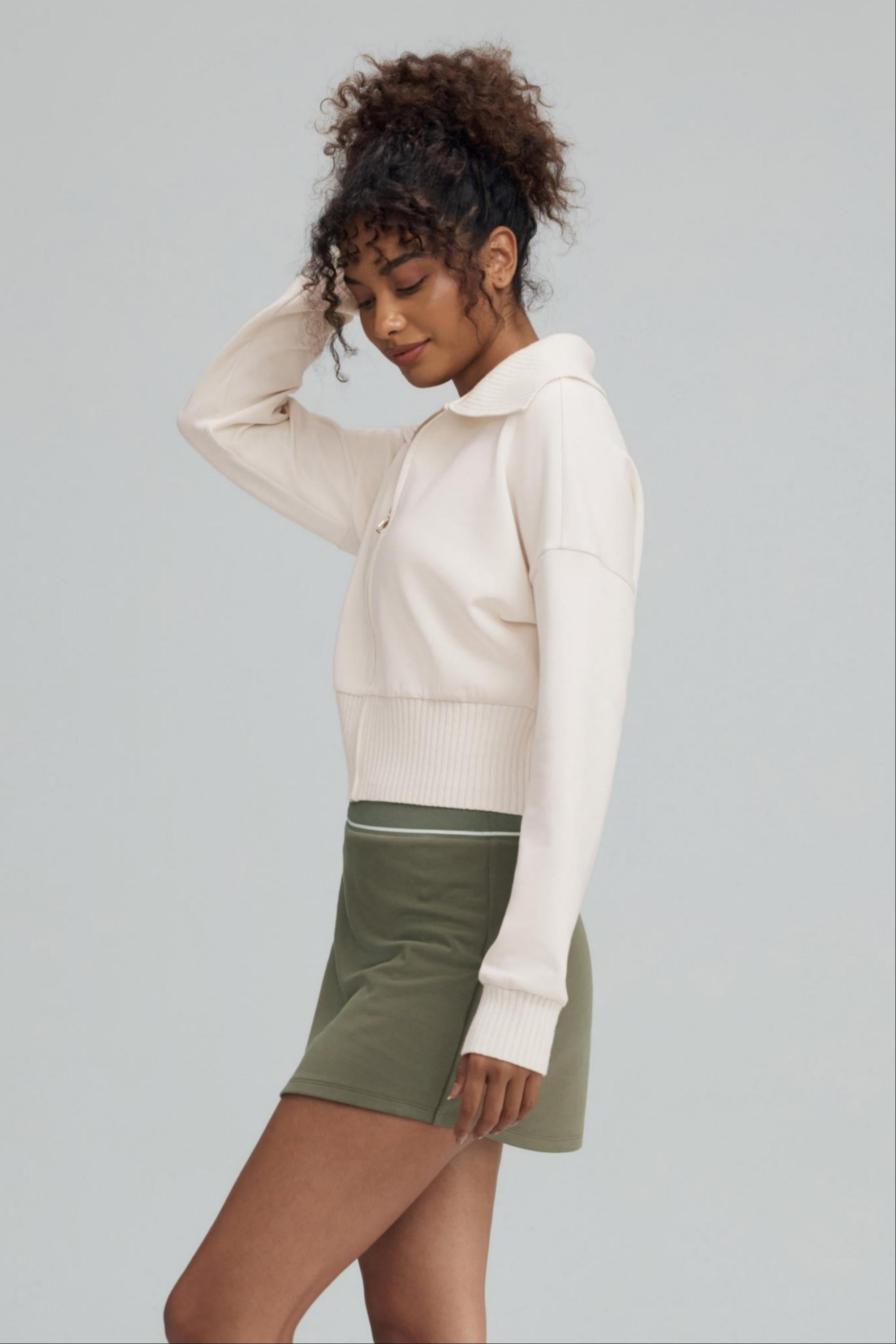 Side view of women’s soft sand cropped knit zip jacket with ribbed waistband