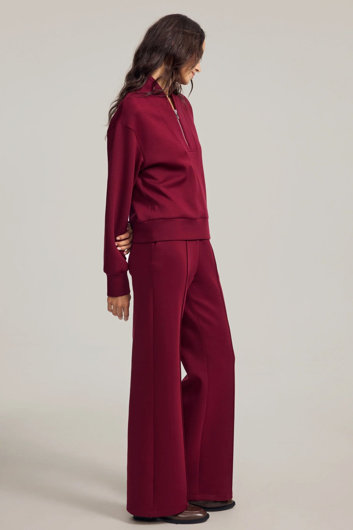 Side view of women's burgundy straight-leg pants showing the fluid drape and wide straight-leg silhouette