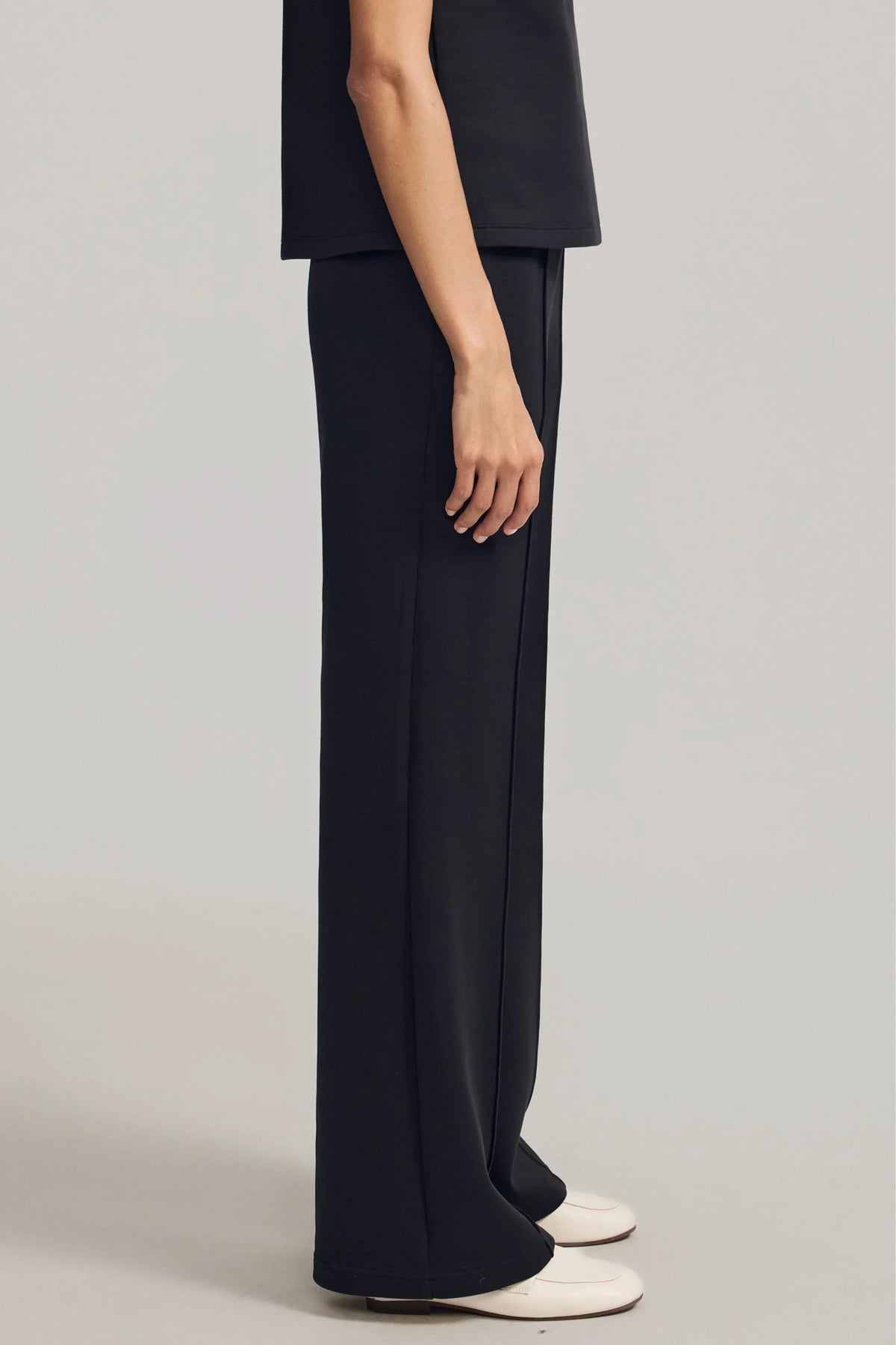 Side view of Onyx Black straight-leg pants showing the smooth drape and relaxed silhouette