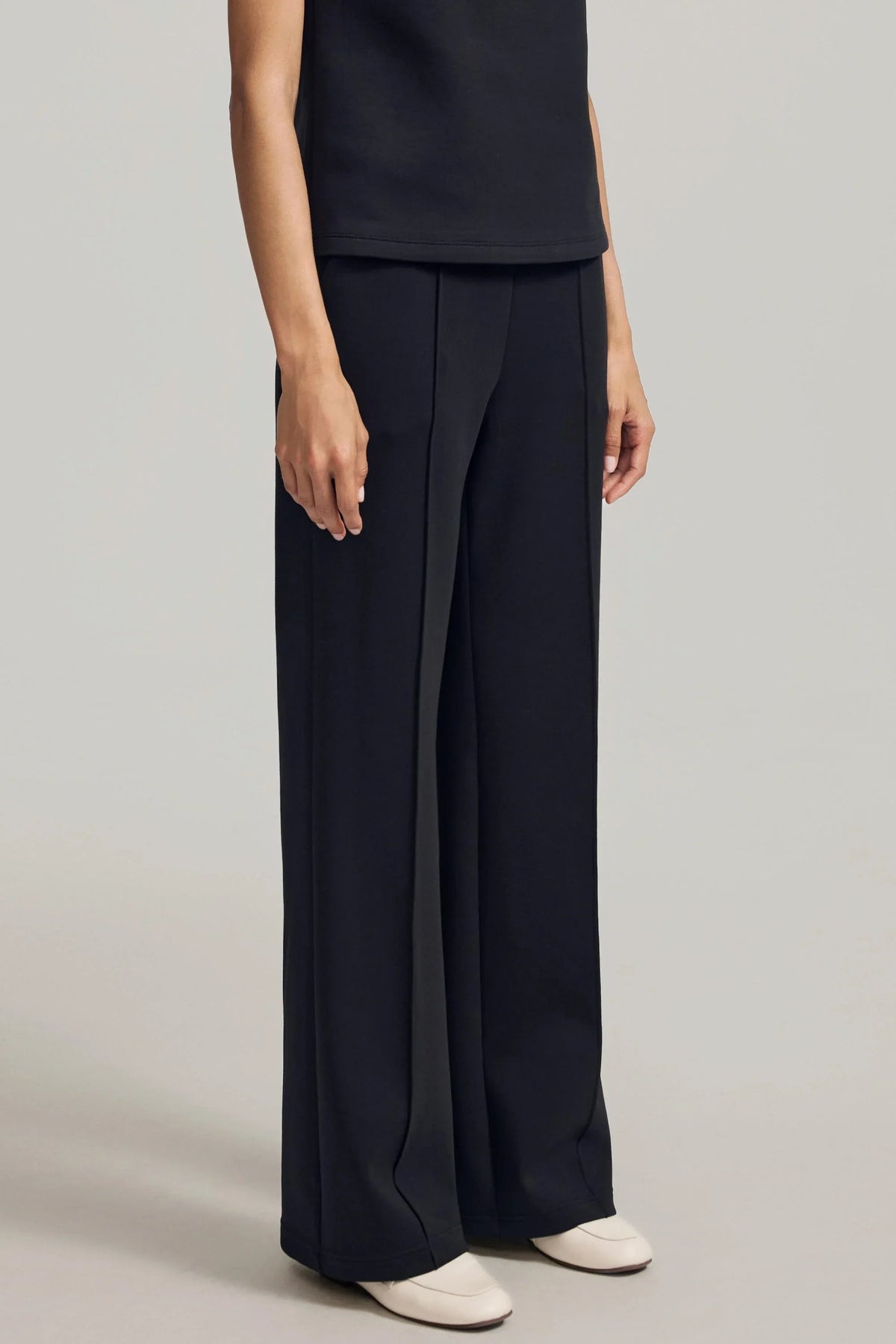 Three-quarter view of women's black straight-leg pants showing the relaxed fit and flowing leg shape
