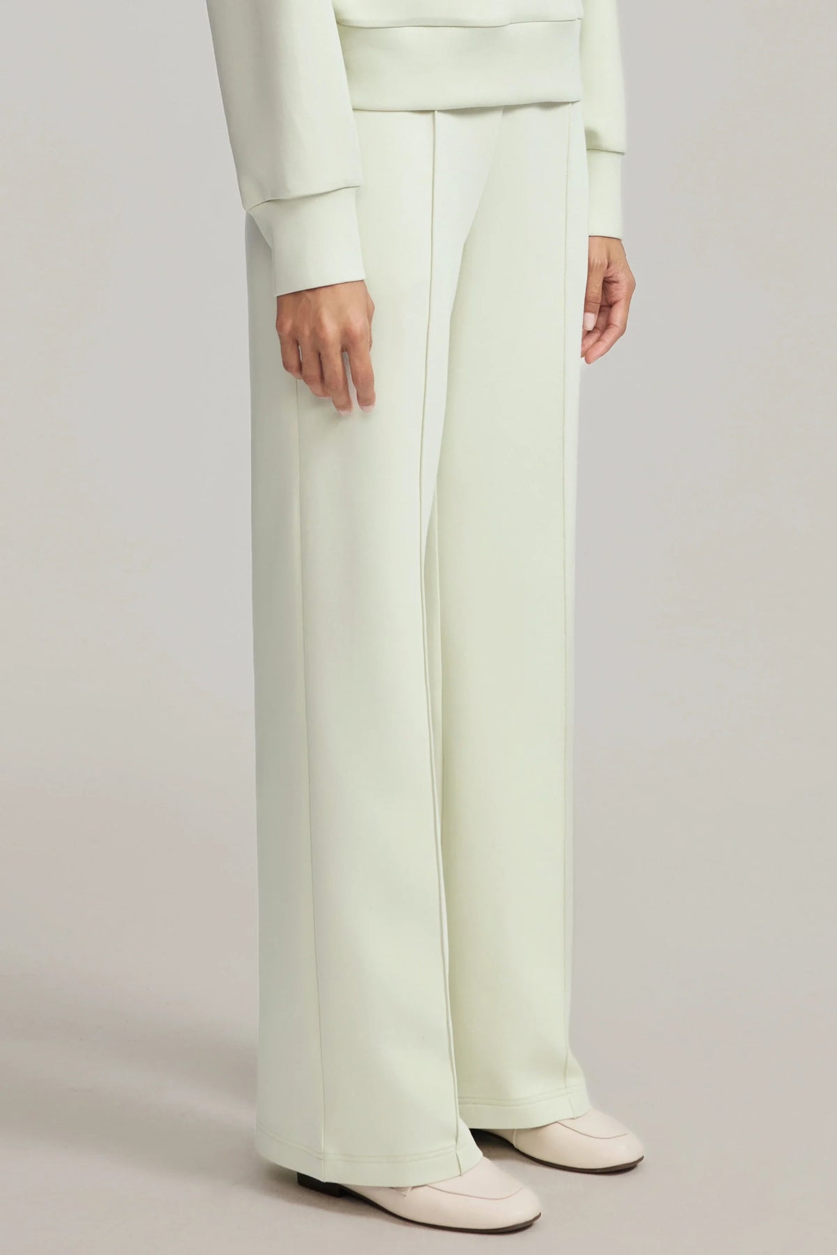 Three-quarter view of women's light green straight-leg pants showing the clean front seams and relaxed fit
