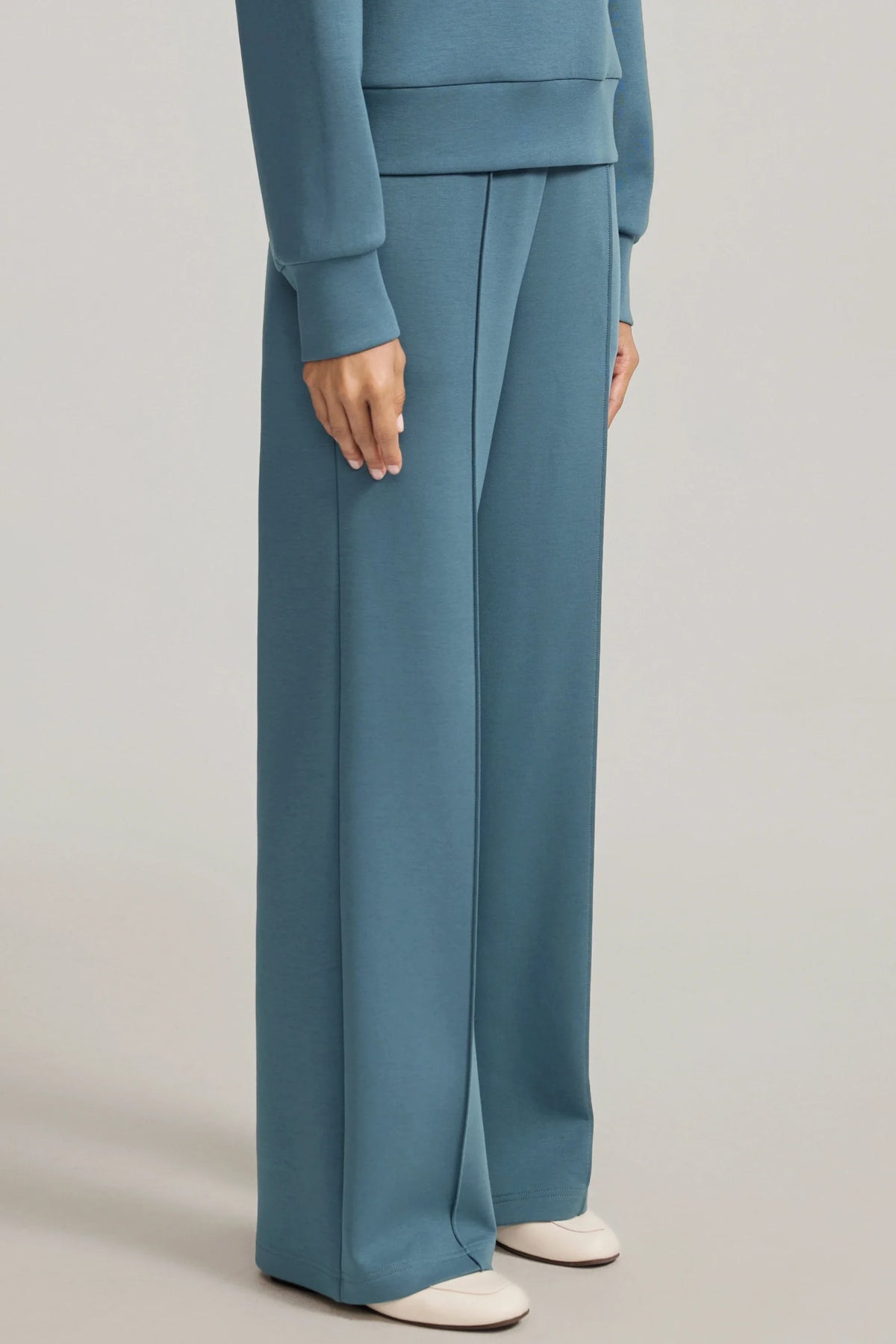 Three-quarter view of women's blue straight-leg pants showing the relaxed fit and front seam details