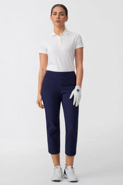 Women wearing midnight navy tailored capri golf pants styled with a white golf polo