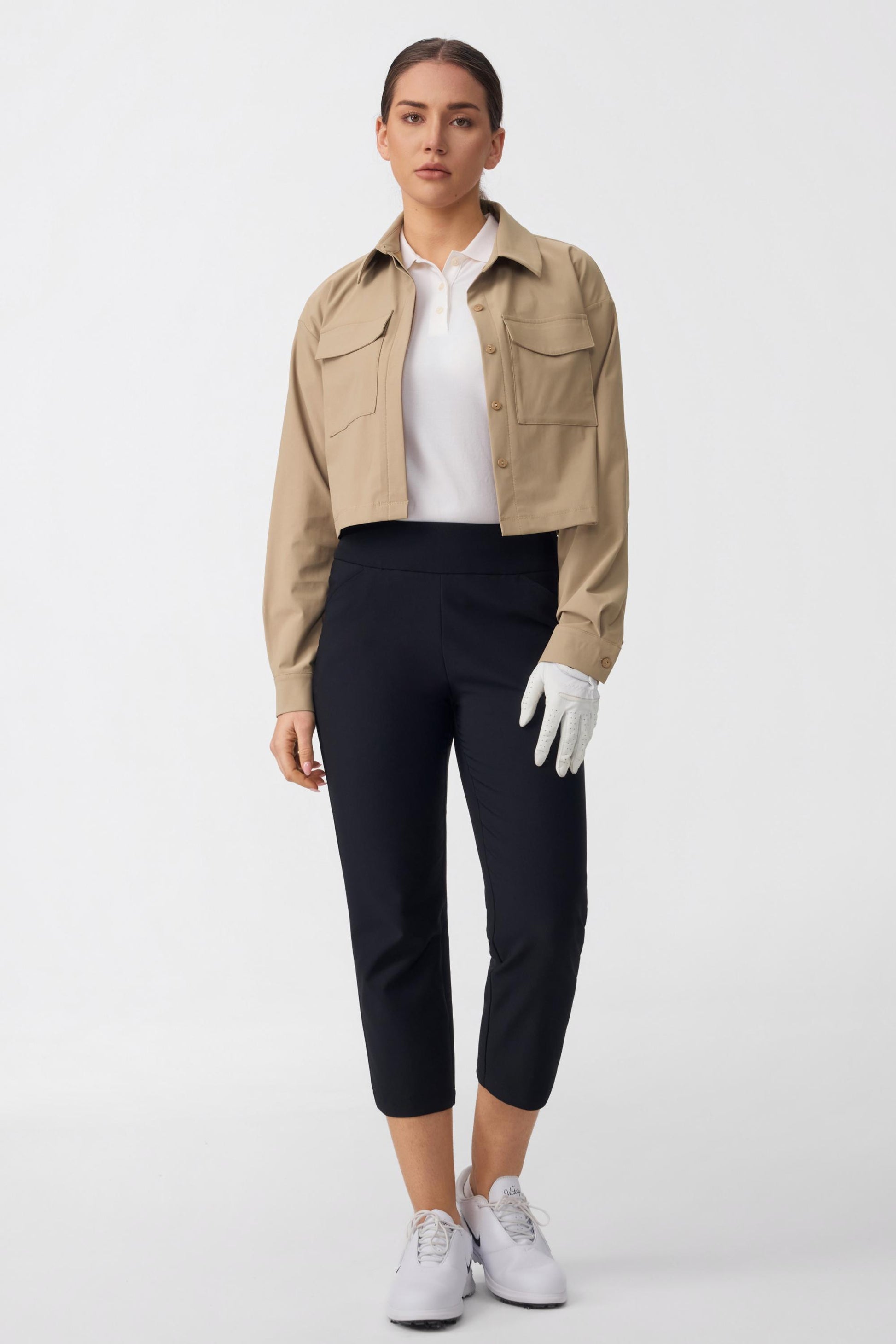 Women’s onyx black tailored capri golf pants styled with a golf outfit featuring a white polo and cropped jacket