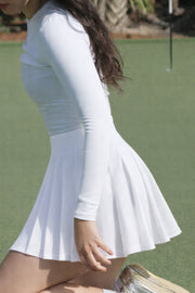 Women’s white pleated golf skort in motion on the golf course, lightweight stretch fabric with a classic flared silhouette