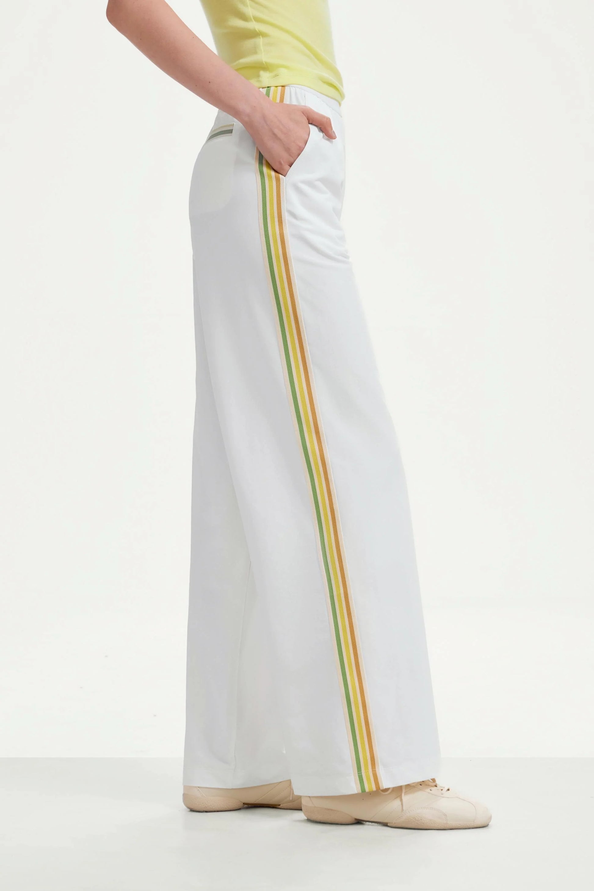 Side view of women’s classic white wide-leg pants with yellow and green side stripes
