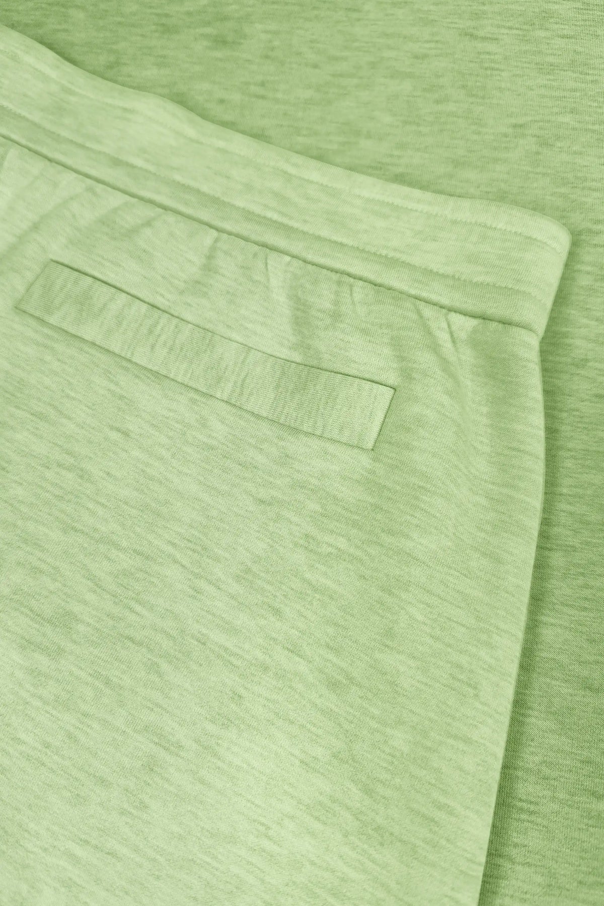 Close-up of the back welt-style pocket and waistband on the women's light green wrap golf skort