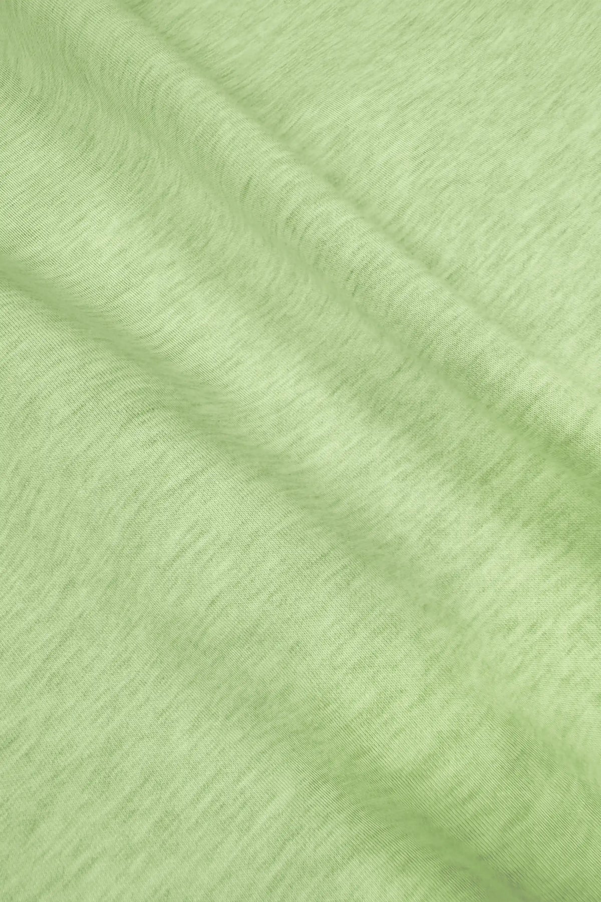 Close-up of soft cotton-modal blend fabric with a subtle knit texture on the lime green golf skort