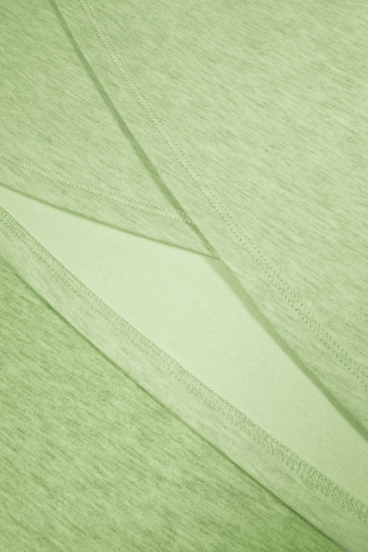 Close-up of overlapping fabric panels and stitching along the wrap-front hem of a light green golf skort