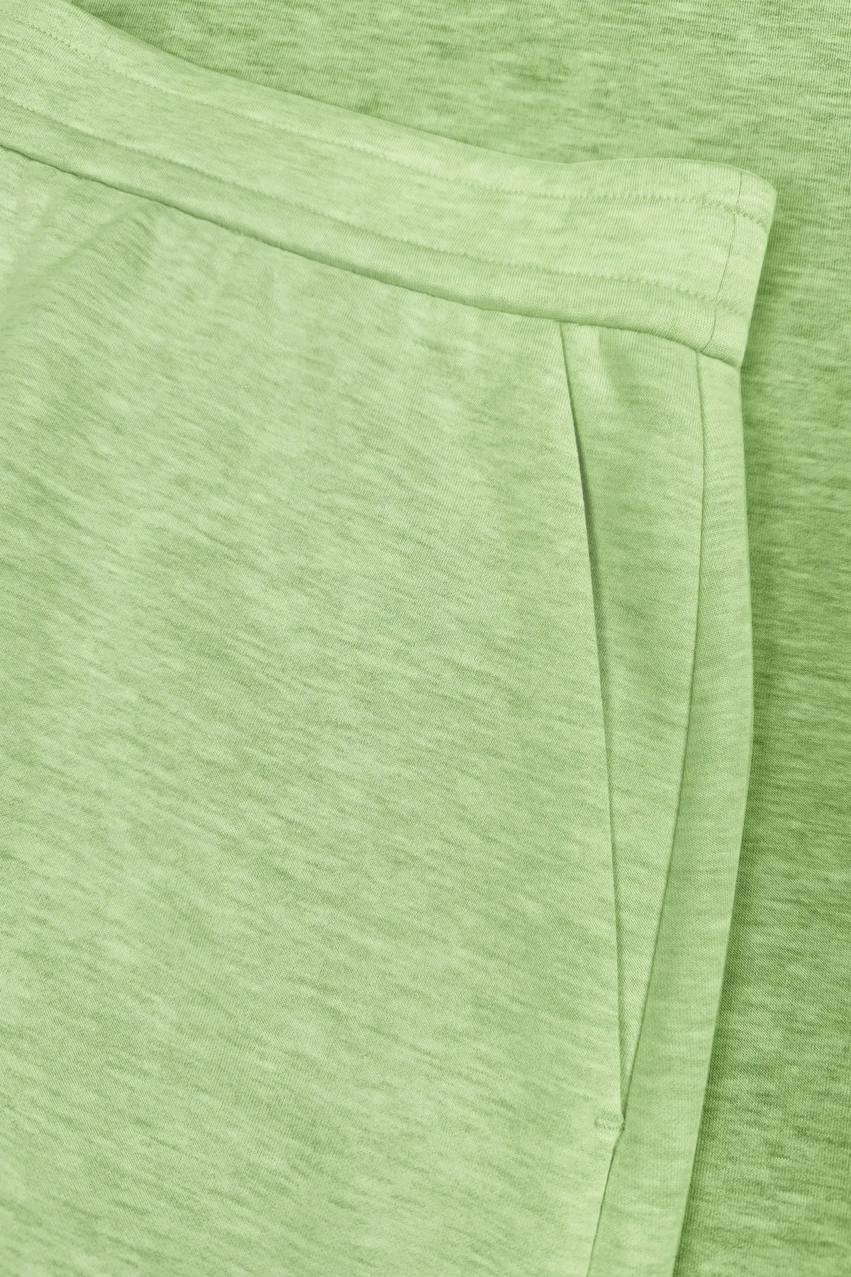 Close-up of the side pocket opening and waistband stitching on the lime green wrap golf skort