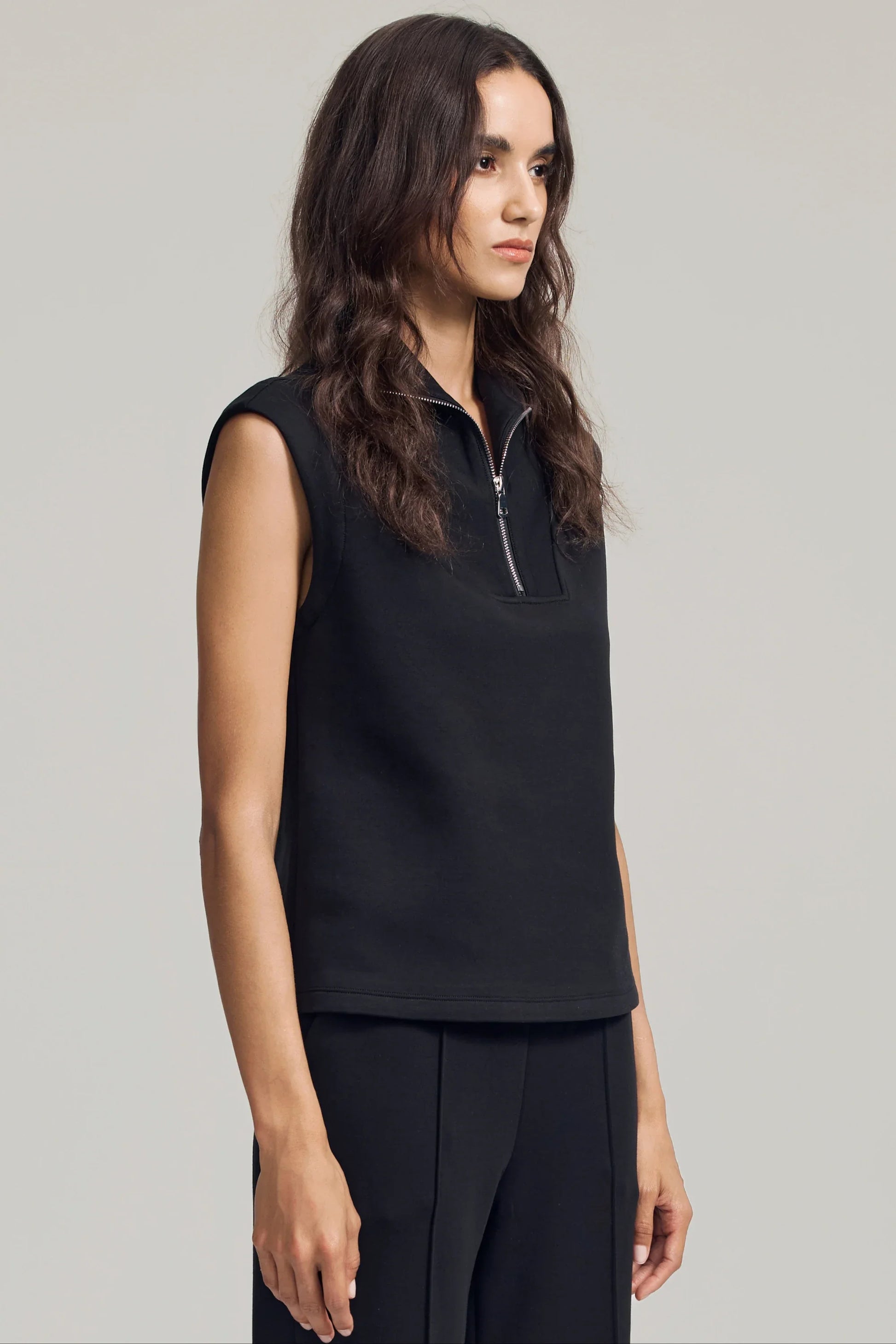 Side view of women’s black sleeveless pullover with modern zip neckline